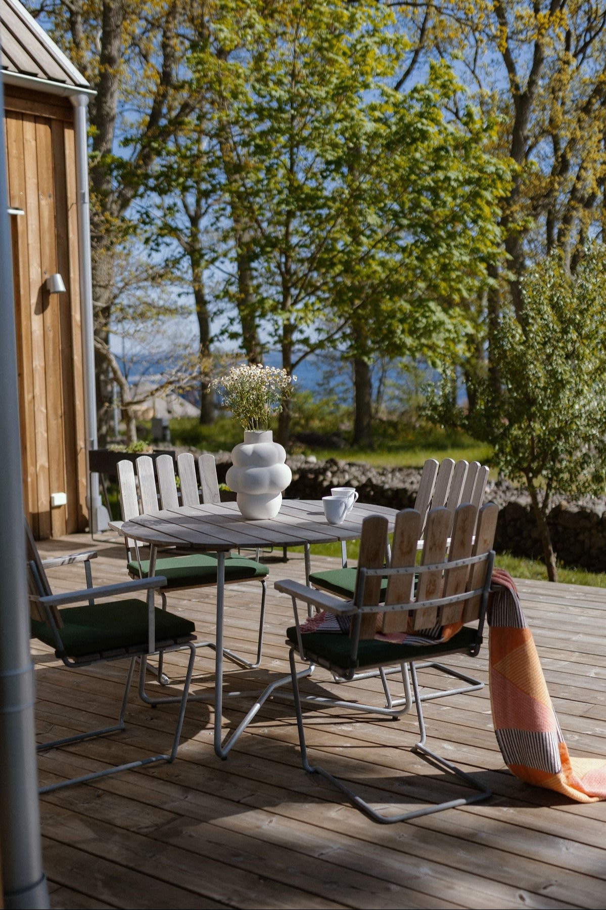Une petite salle à manger confortable sur une terrasse en bois avec des chaises A2 de Grythyttan.