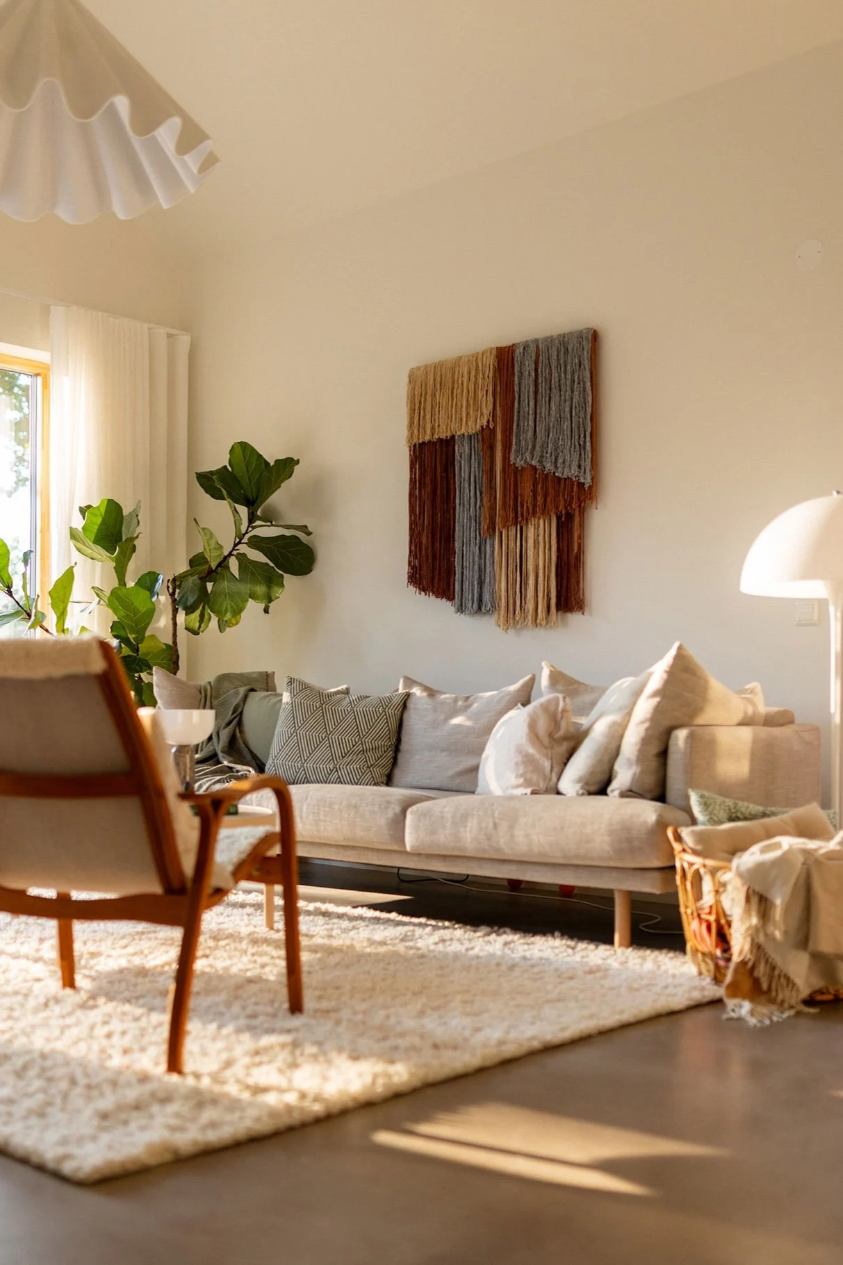 La décoration murale en tissu Tham de Tinted est accrochée au mur d'un salon, au-dessus d'un canapé. 