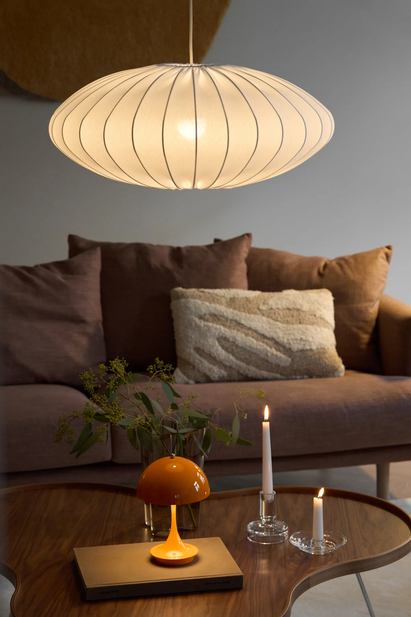 La suspension Ellipse avec abat-jour en tissu de Watt & Veke est suspendue dans un salon confortablement aménagé.