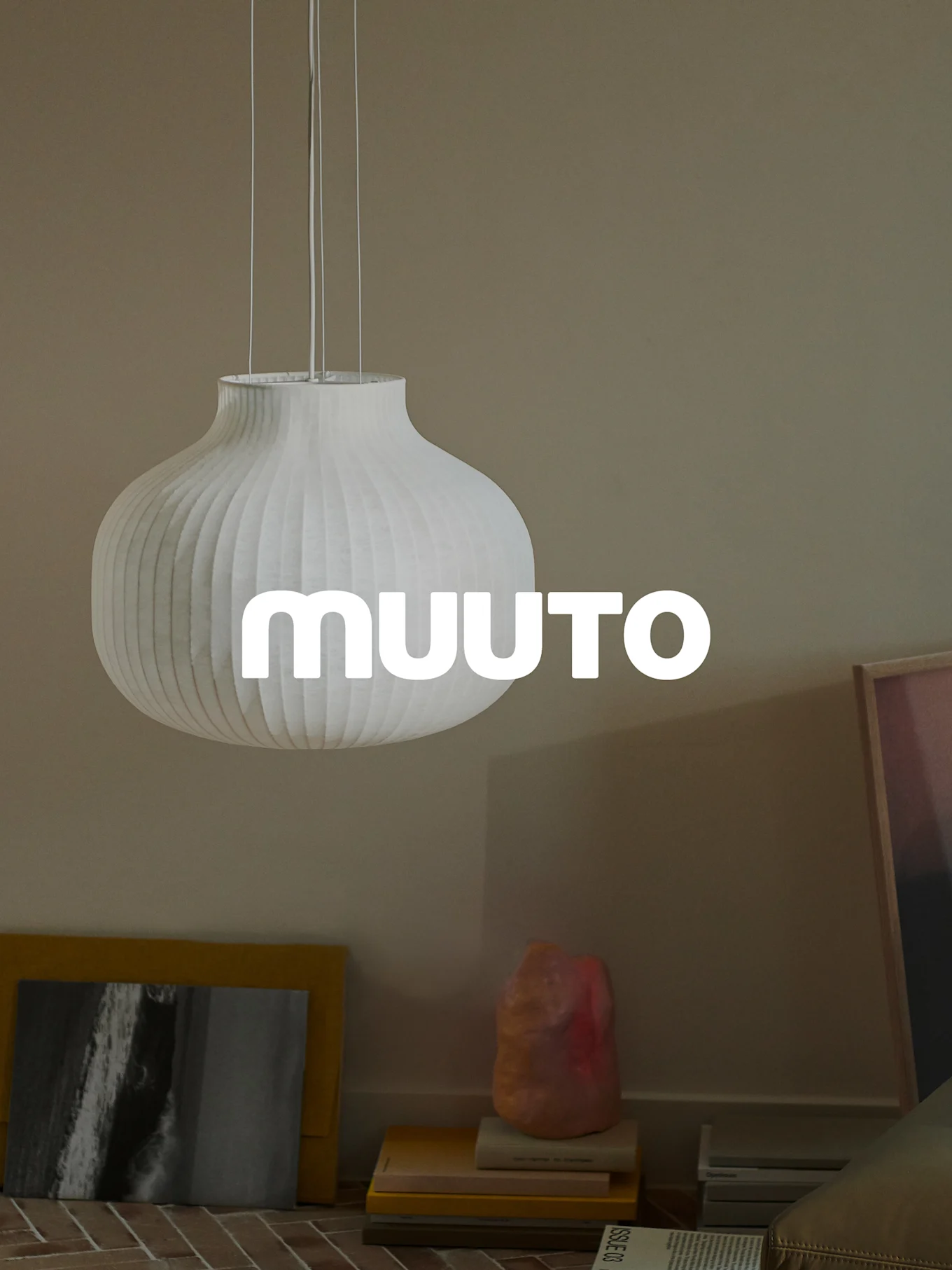 Suspension blanche côtelée en forme de gourde avec le logo 'MUUUTO', dans une pièce beige.