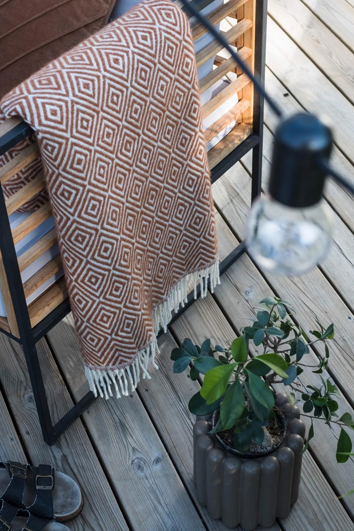 Le pot de fleurs marron Mist de DBKD se trouve sur la terrasse à côté d'un banc avec une couverture dans la maison de @lindaz.se.