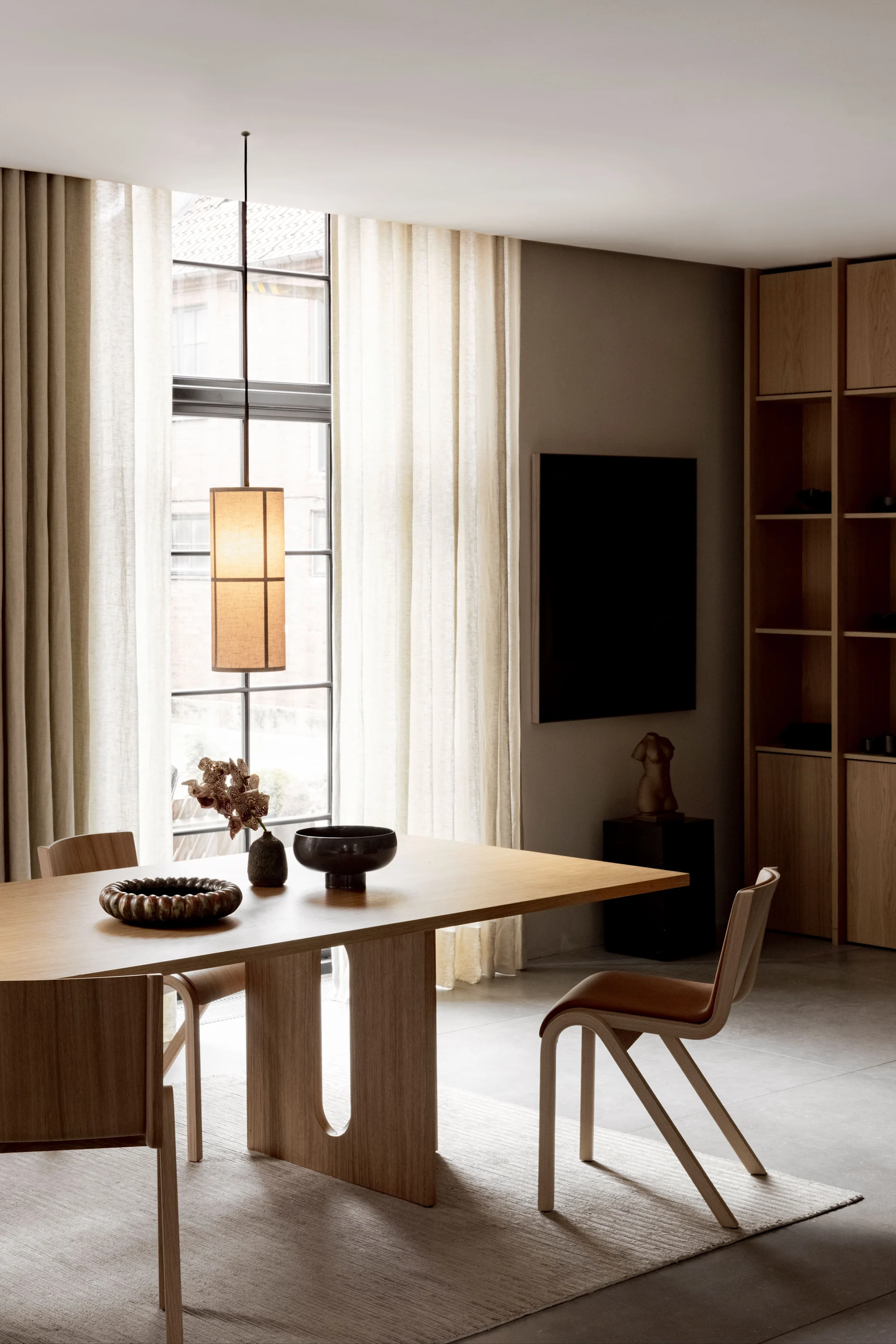 Une salle à manger avec des meubles Audo Copenhagen est éclairée par la suspension Hashira.