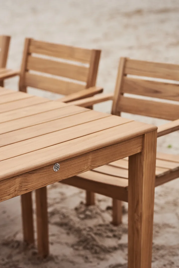 Table de salle à manger extérieure en bois avec chaises sur le sable, dotée d'une plaque '188'.