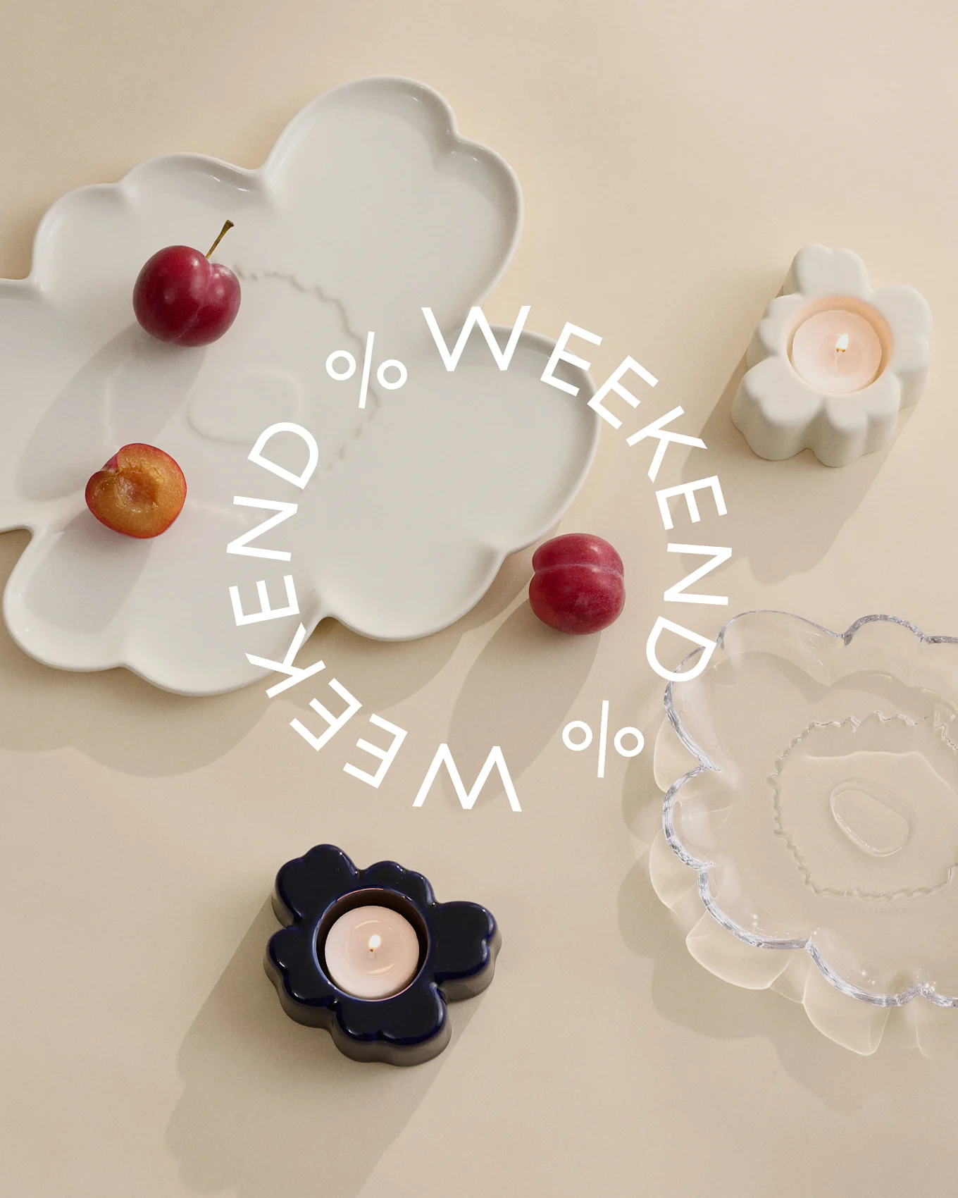 Assiettes décoratives et bougeoirs en verre blanc, bleu et transparent avec des prunes sur fond beige. Texte blanc 'Weekend %'.