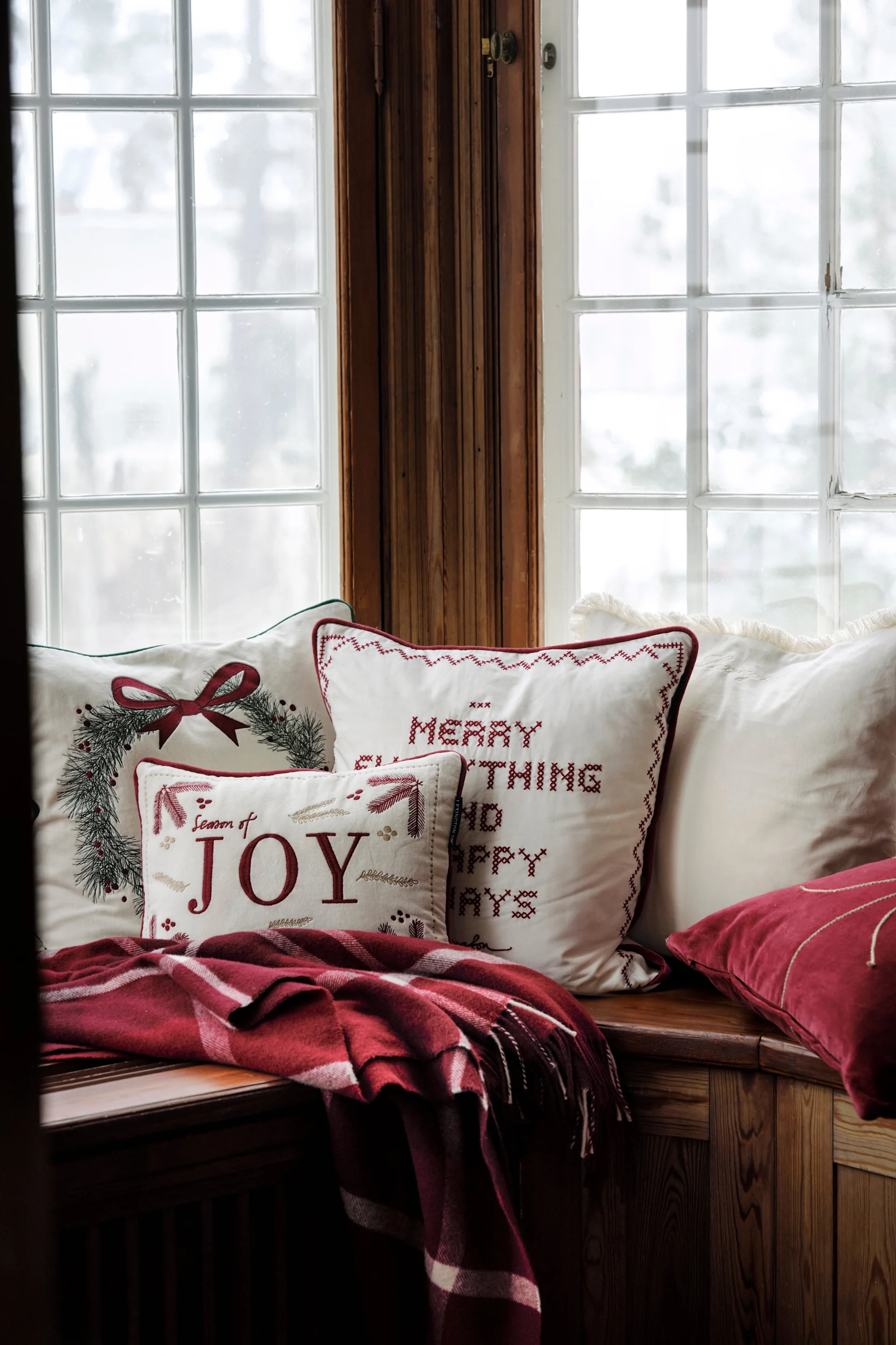 Les coussins de Noël font partie intégrante de la décoration de Noël scandinave. Ici, plusieurs coussins ornés de motifs de Noël de Lexington sont disposés sur un rebord de fenêtre.