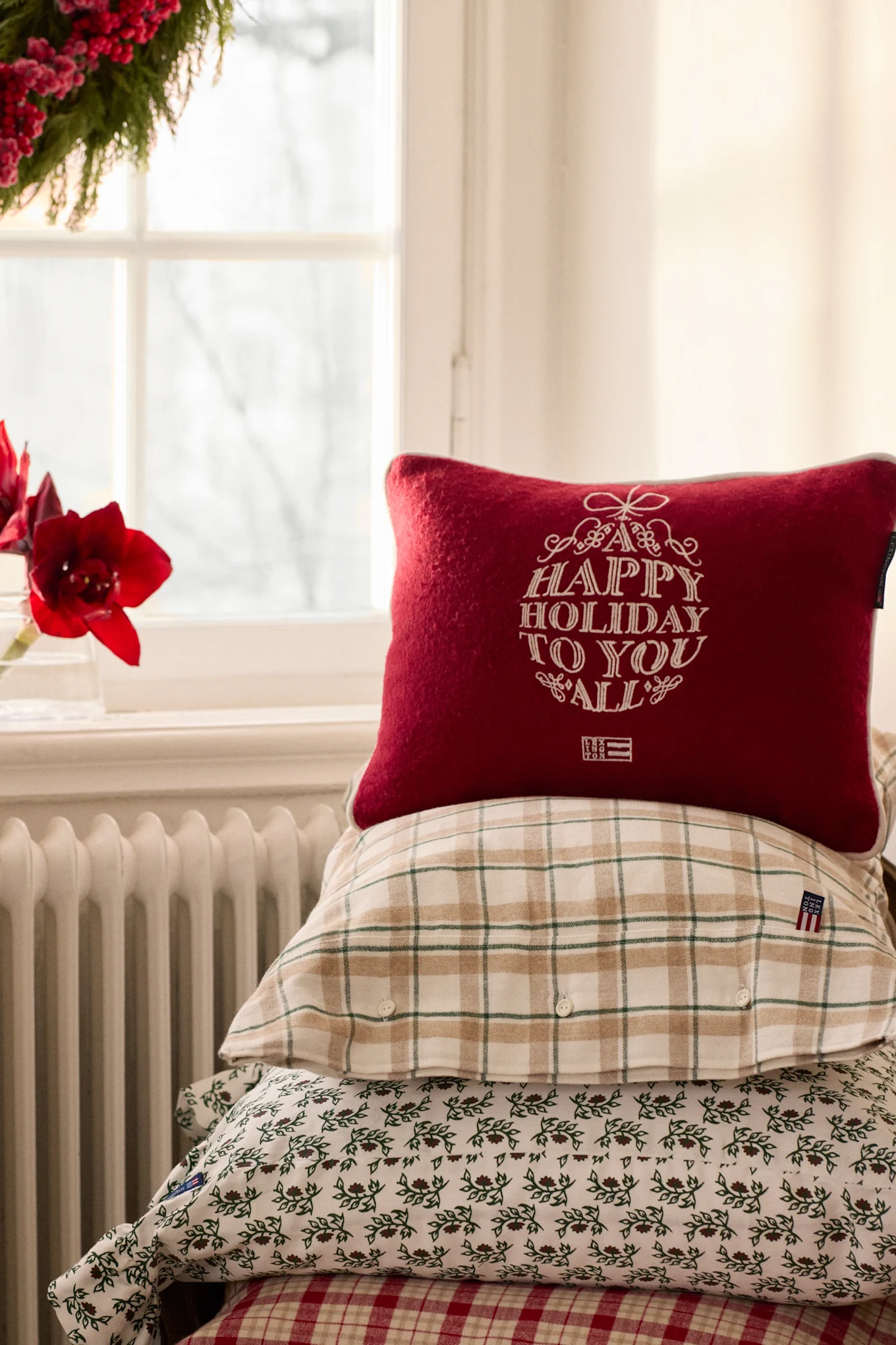 Les coussins de Noël font partie intégrante de la décoration de Noël scandinave. Ici, plusieurs coussins ornés de motifs de Noël de Lexington sont disposés sur un rebord de fenêtre.