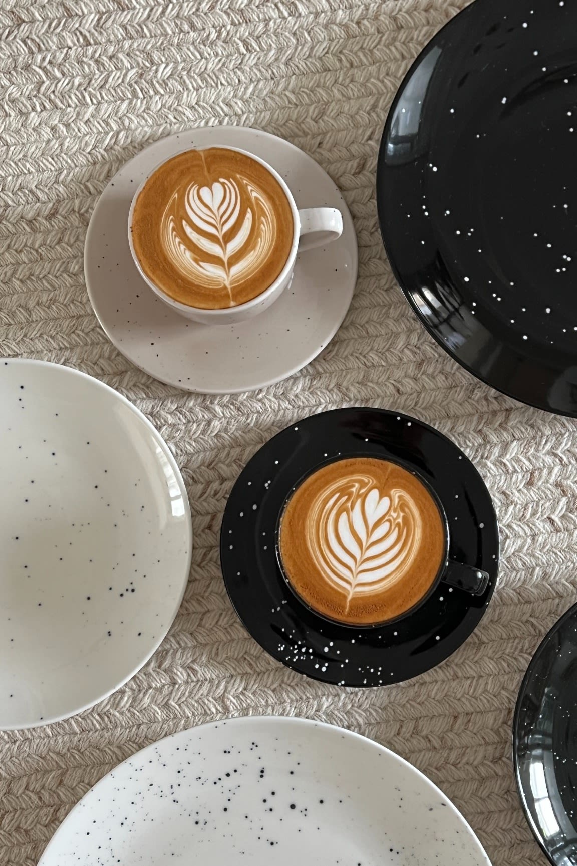 Deux tasses de café artistiquement disposées en noir et beige de la collection Freckle de Scandi Living, entourées d'assiettes dans la maison de @Avery-P.