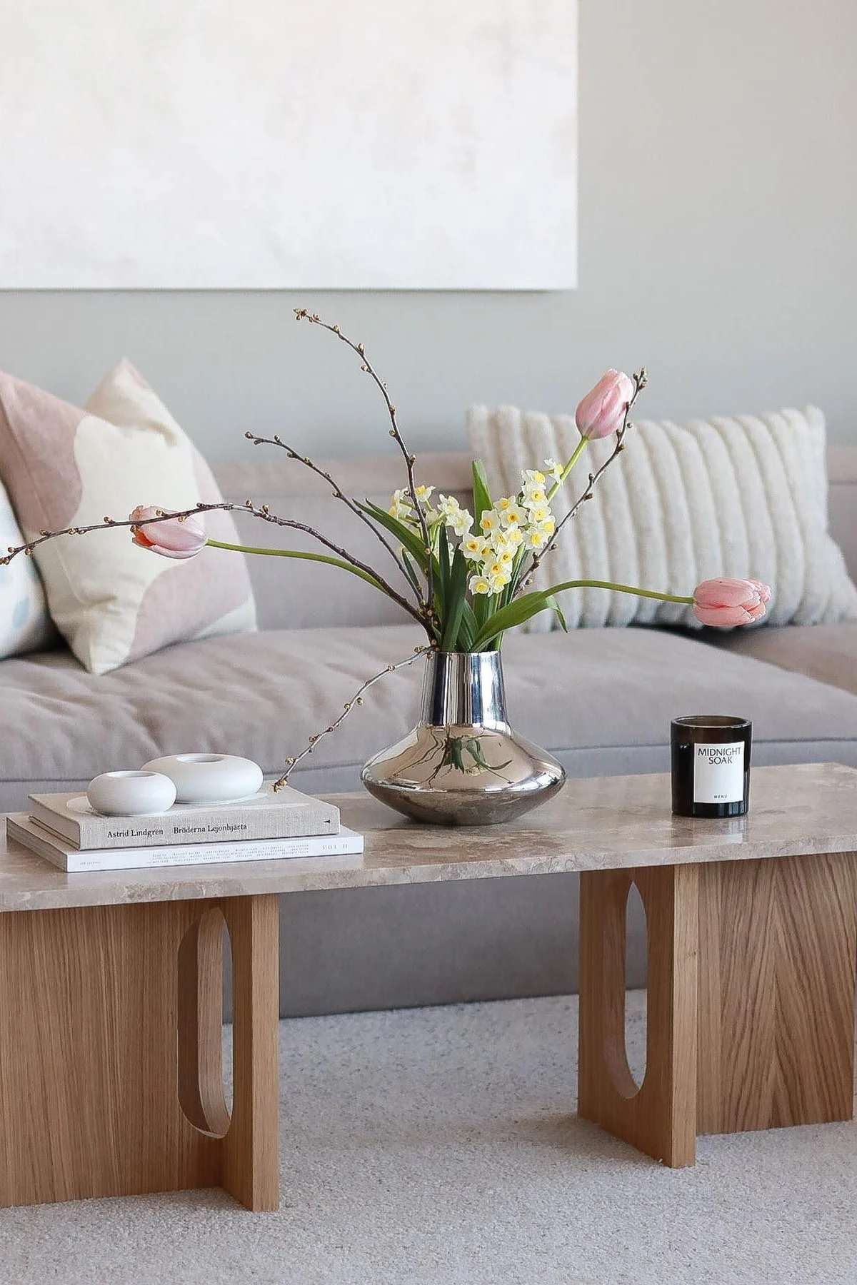 Une table basse printanière décorée par @picsbyellen : sur la table basse Androgyne de Audo Copenhagen, se trouve le vase chromé Henning Koppel de Georg Jensen avec des tulipes, accompagné de bougies et de bougeoirs.