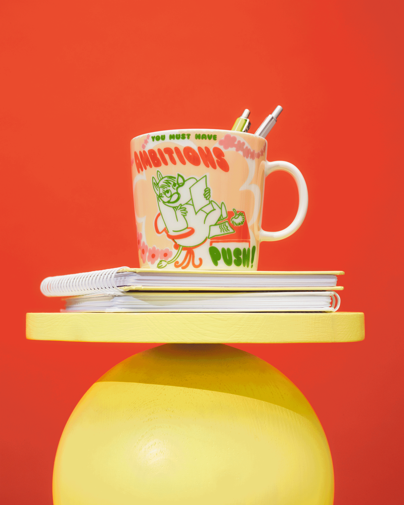 Quatre tasses colorées à thème Moomin sur des présentoirs jaunes et rouges devant un fond rouge.