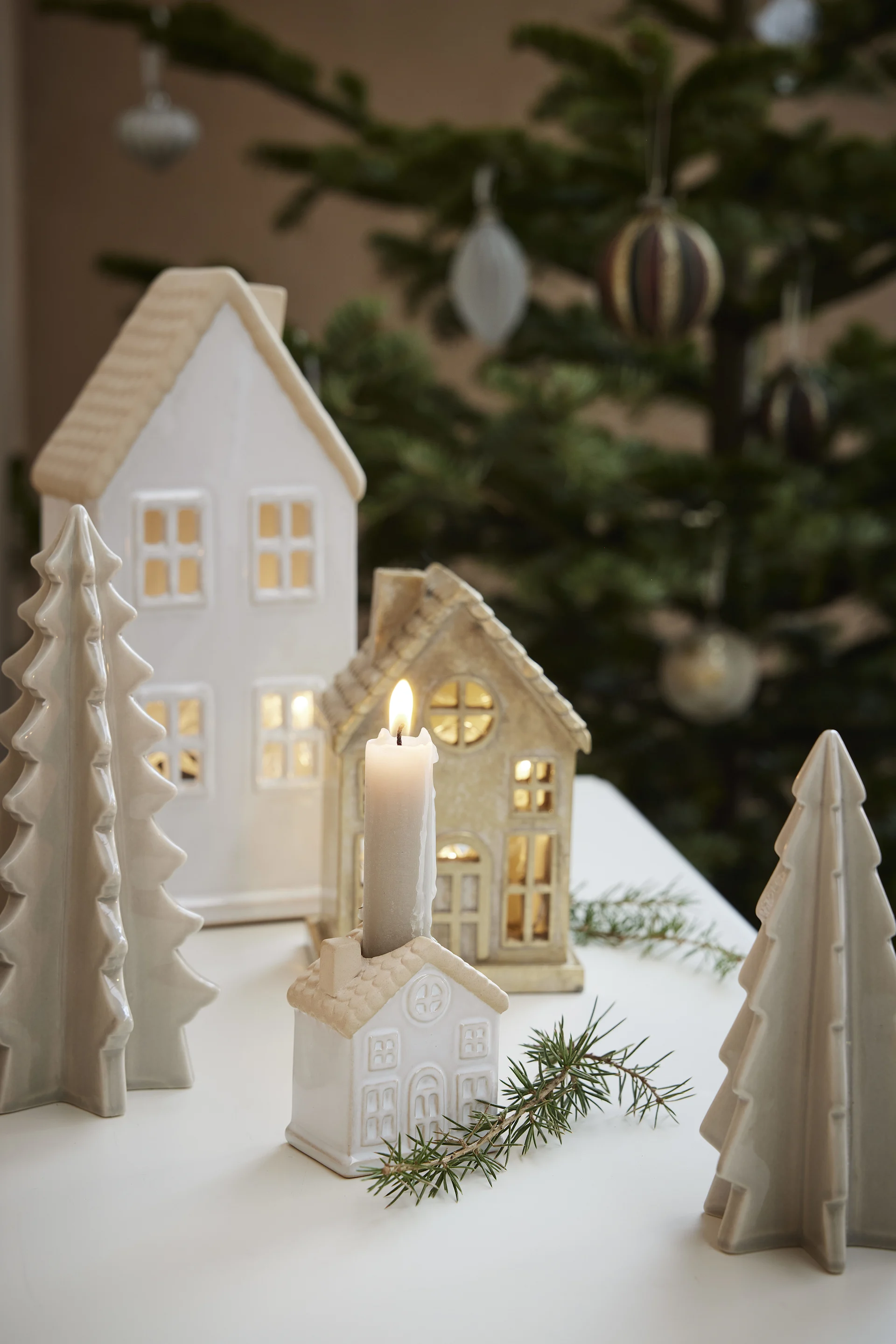 Décoration de Noël scandinave : plusieurs maisons lumineuses de Lene Bjerre sont disposées sur une table.