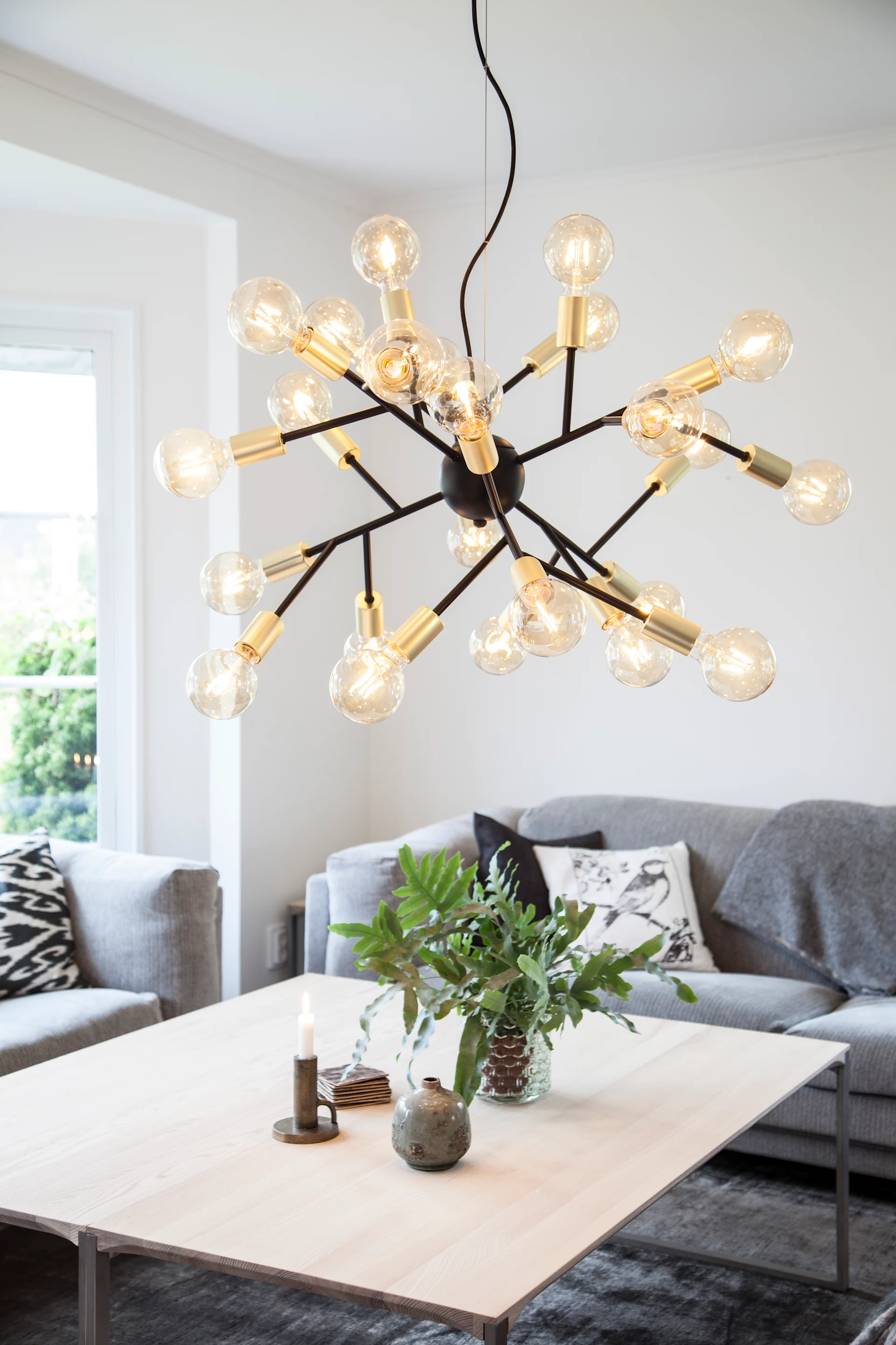 Au-dessus d'une table basse est suspendu l'extraordinaire plafonnier Heroes de By Rdens.