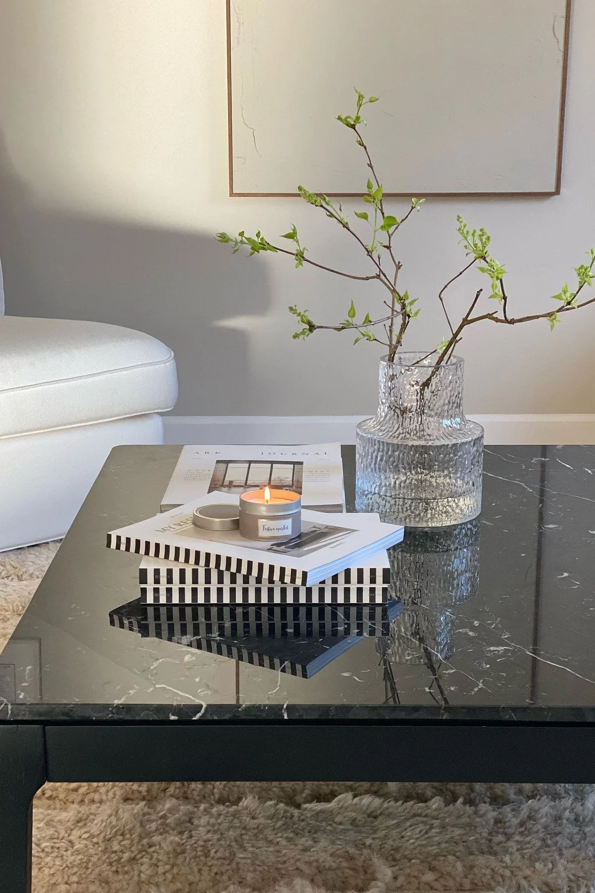 Une table basse noire, décorée de livres et du vase Skrufs Kolonn.