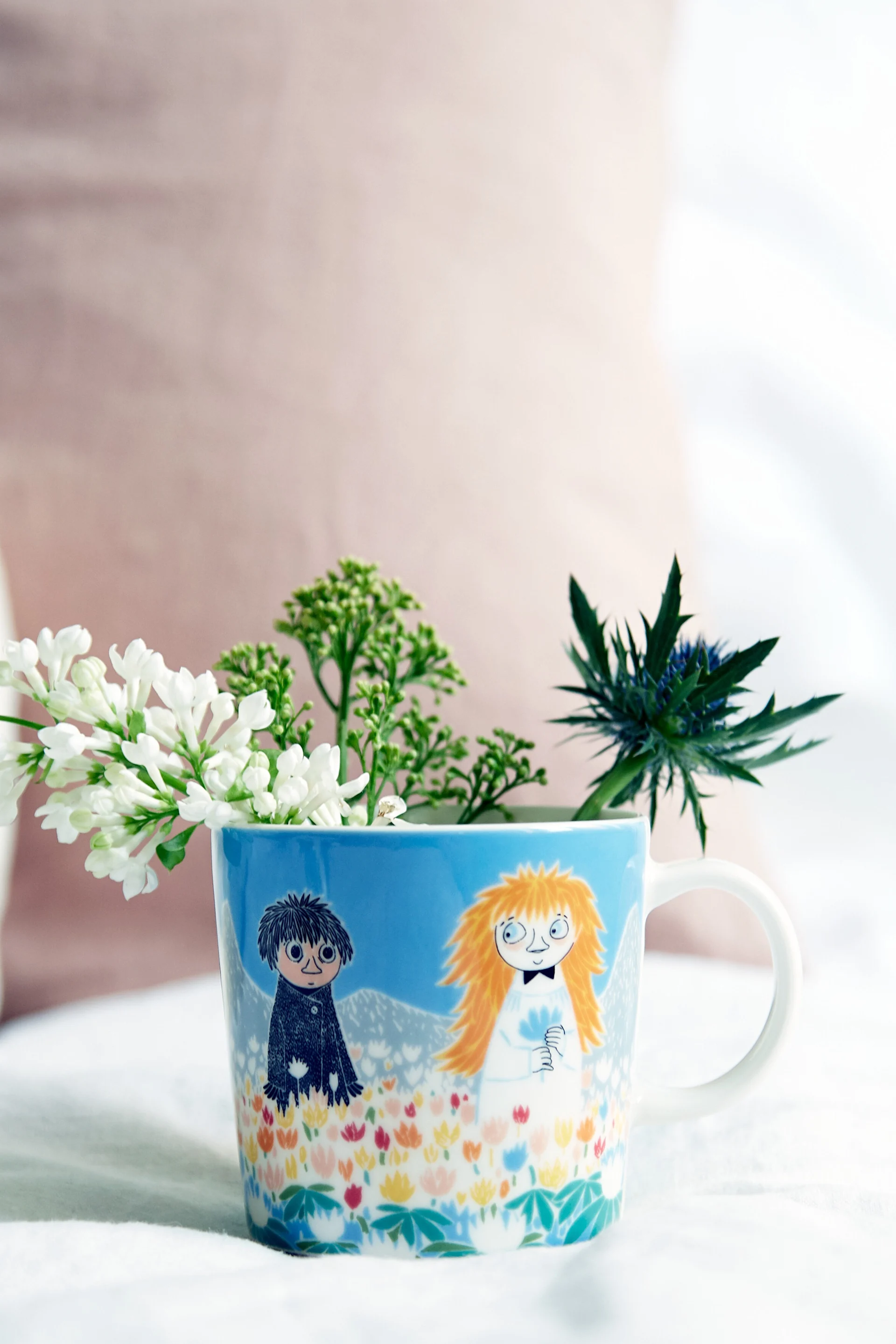 La tasse Moomin « Friendship » est posée sur une table avec des fleurs à l'intérieur.