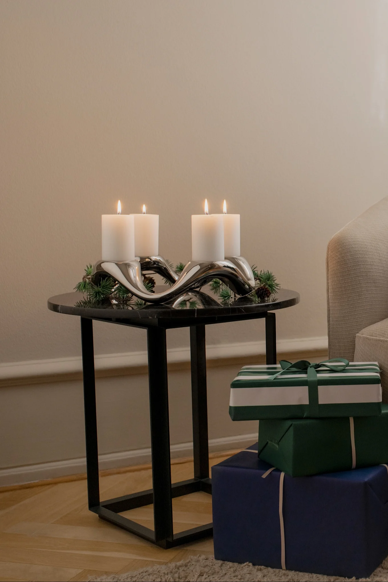 Le bougeoir Cobra de Georg Jensen, décoré de branches de sapin, est posé sur une table d'appoint.