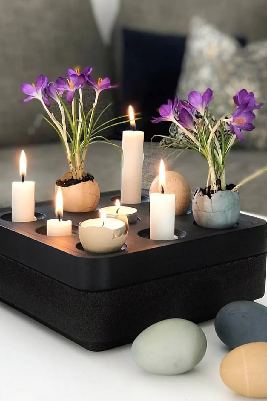 Un bougeoir noir Stumpastaken de Born in Sweden est décoré de bougies et d'œufs colorés avec des fleurs à l'intérieur pour Pâques. @dallasvillan