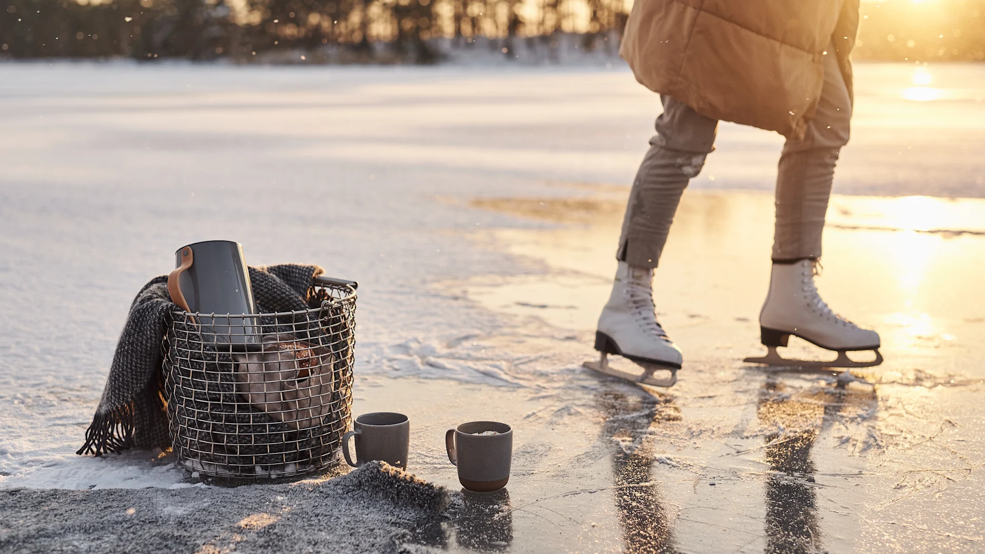Le style de vie scandinave à essayer cet hiver - patiner sur un lac avec un panier Korbo rempli d'un thermos et de nombreuses couvertures en laine.