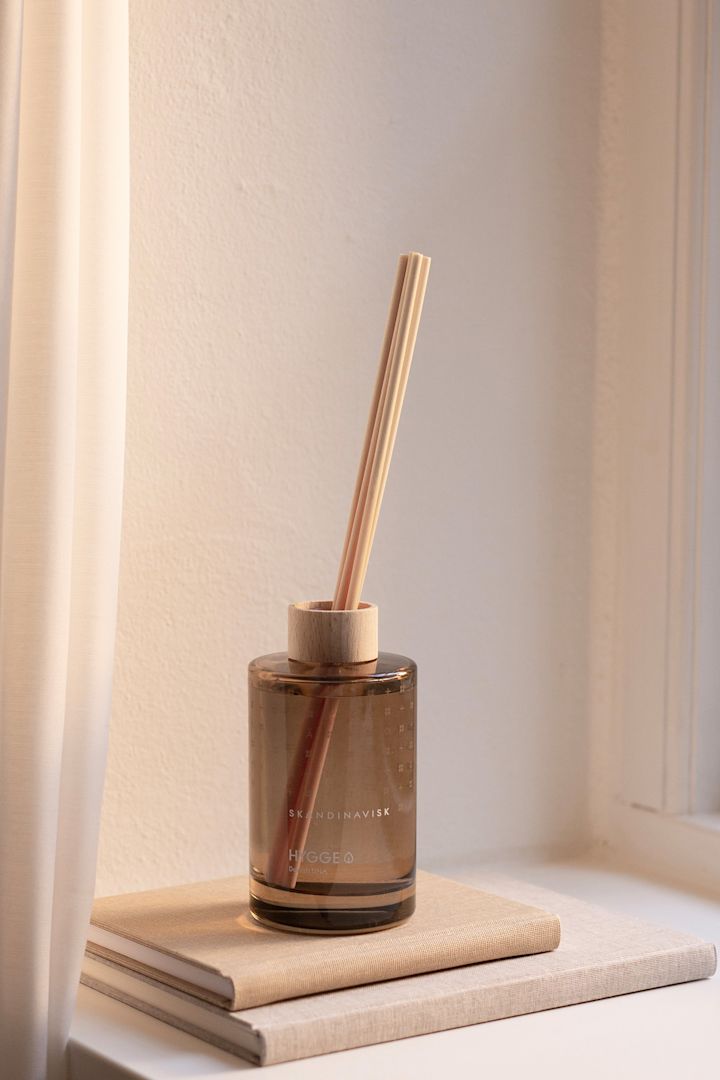 Une chambre Feng Shui doit également dégager une odeur agréable. Ici, les bâtonnets parfumés Hygge de Skandinavisk sont posés sur deux livres, sur le rebord d'une fenêtre.