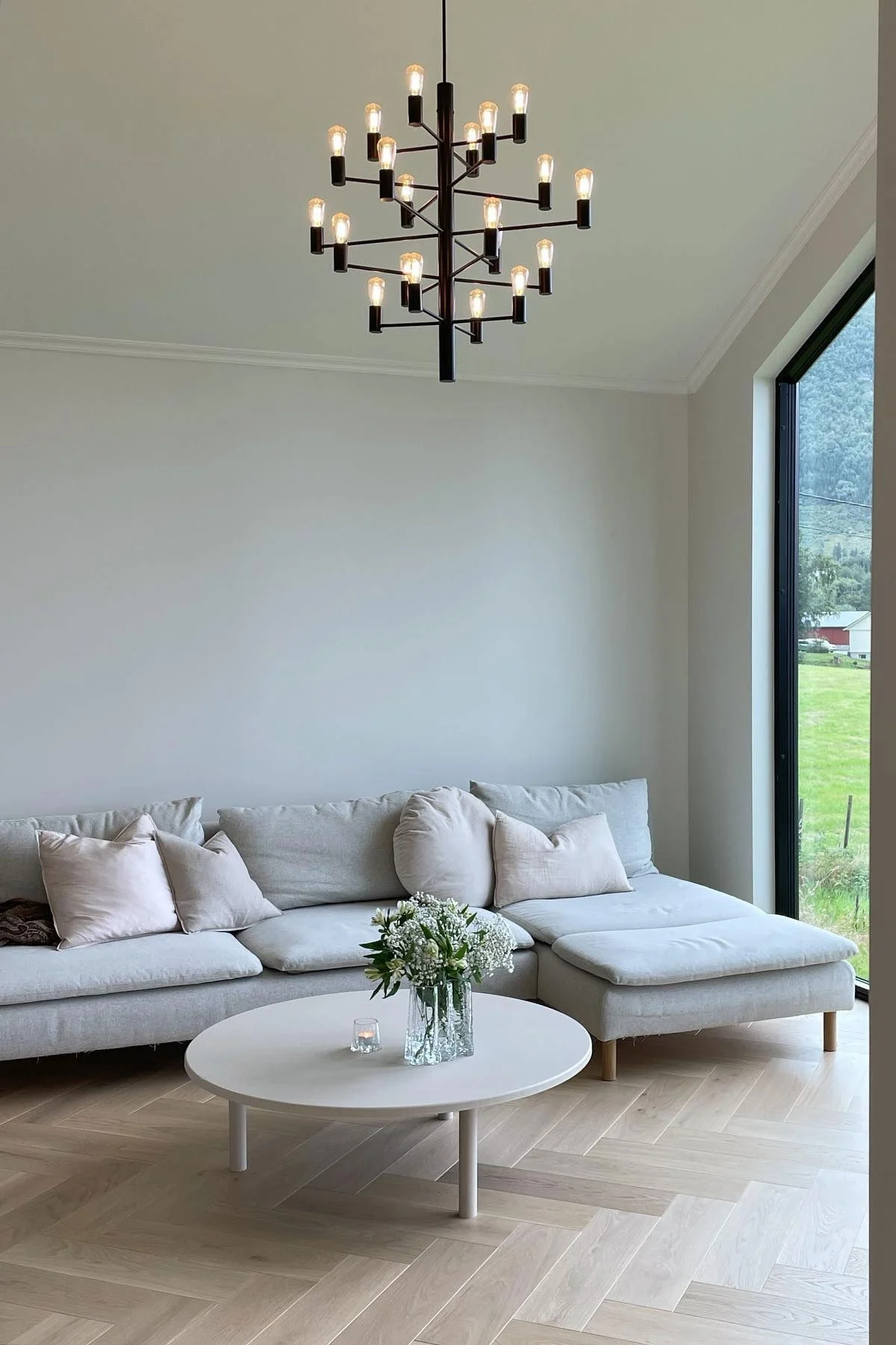 Le lustre Manola 20 de Herstal est suspendu dans le salon minimaliste de @villa_granset.