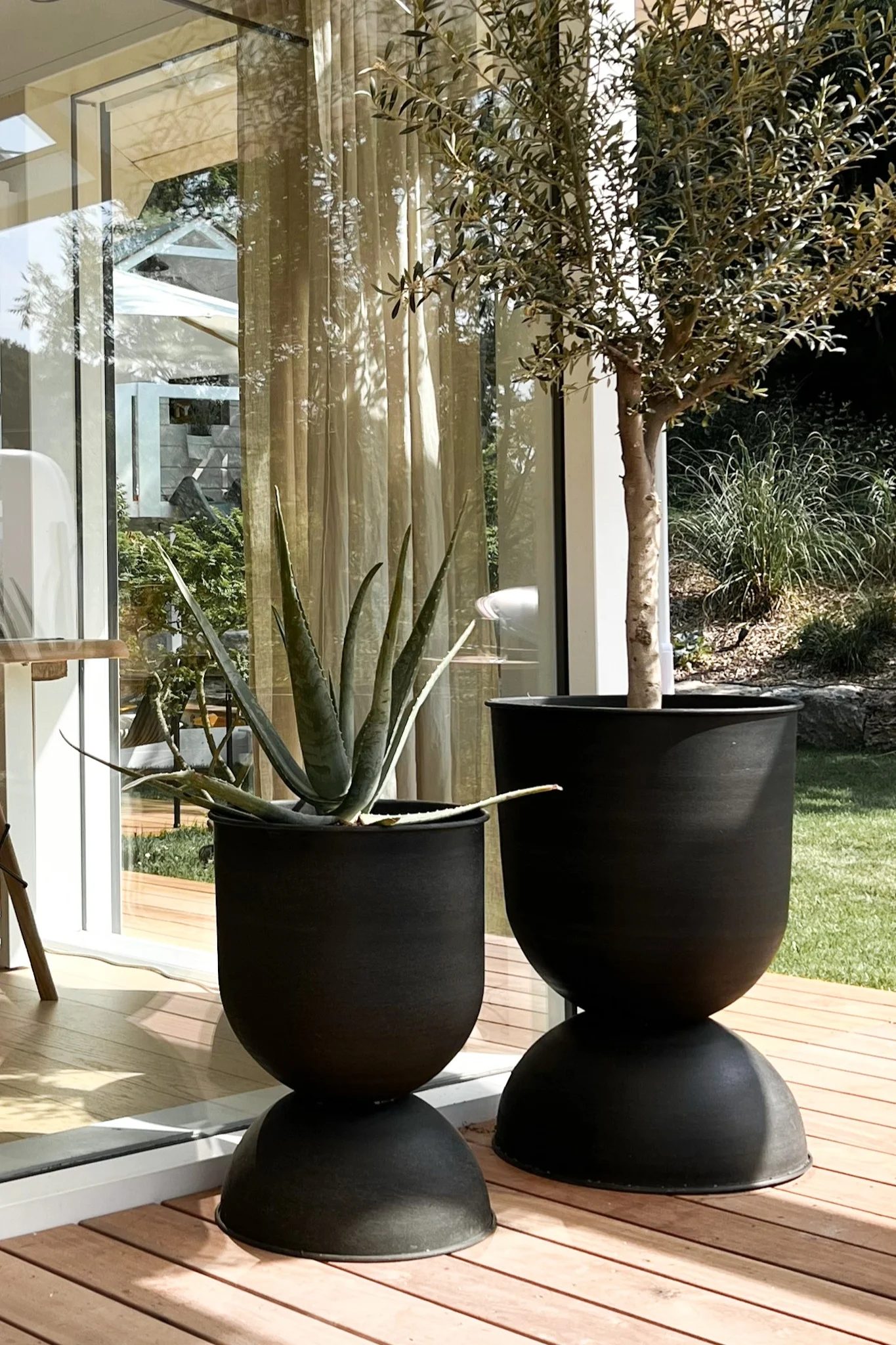 La grande jardinière d'extérieur Hourglass de Ferm Living est posée en paire sur la terrasse de la maison. 
