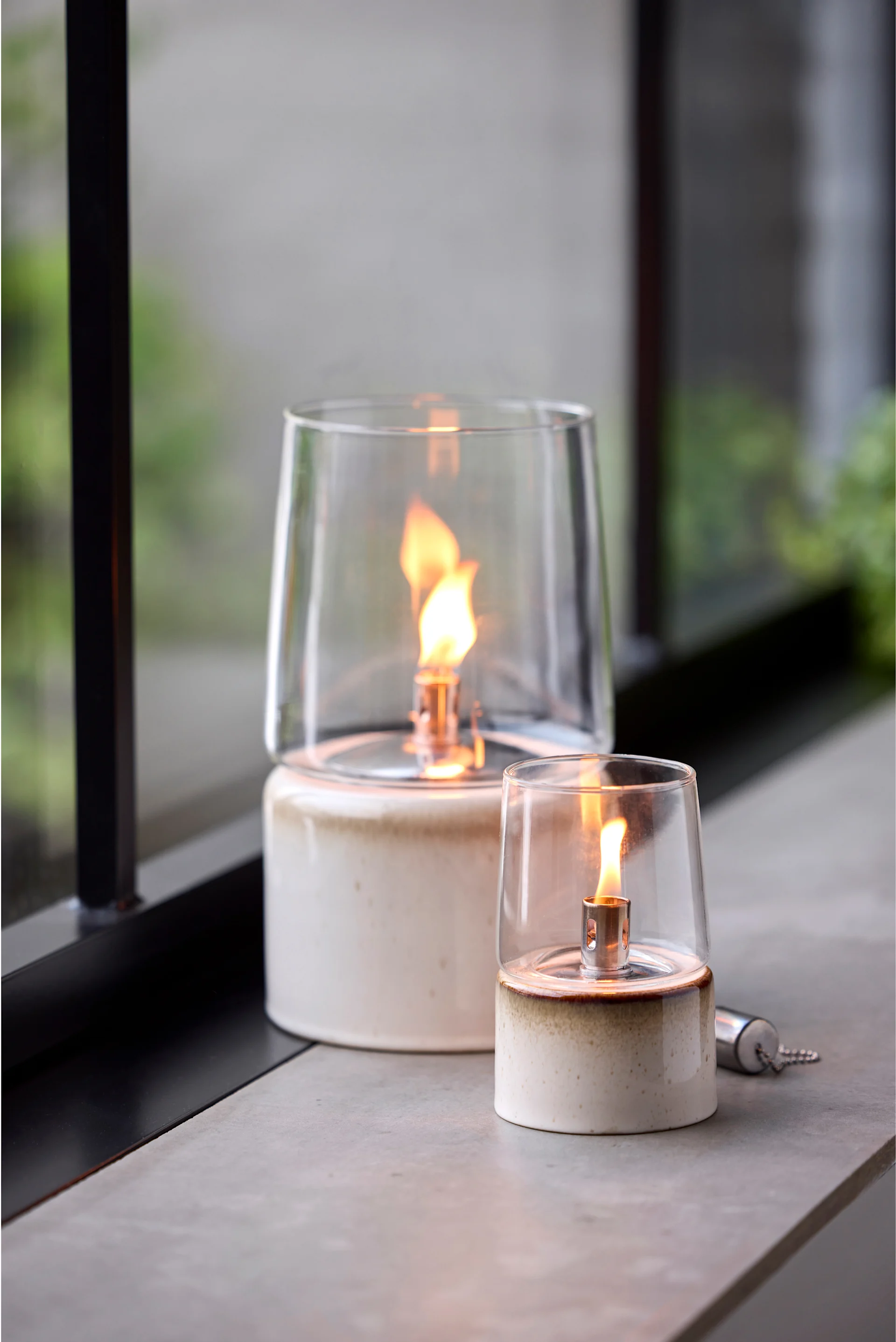 Placez des lanternes et des photophores d'extérieur sur votre balcon, votre terrasse ou dans votre jardin, par exemple l'élégante lampe à huile de Stelton.