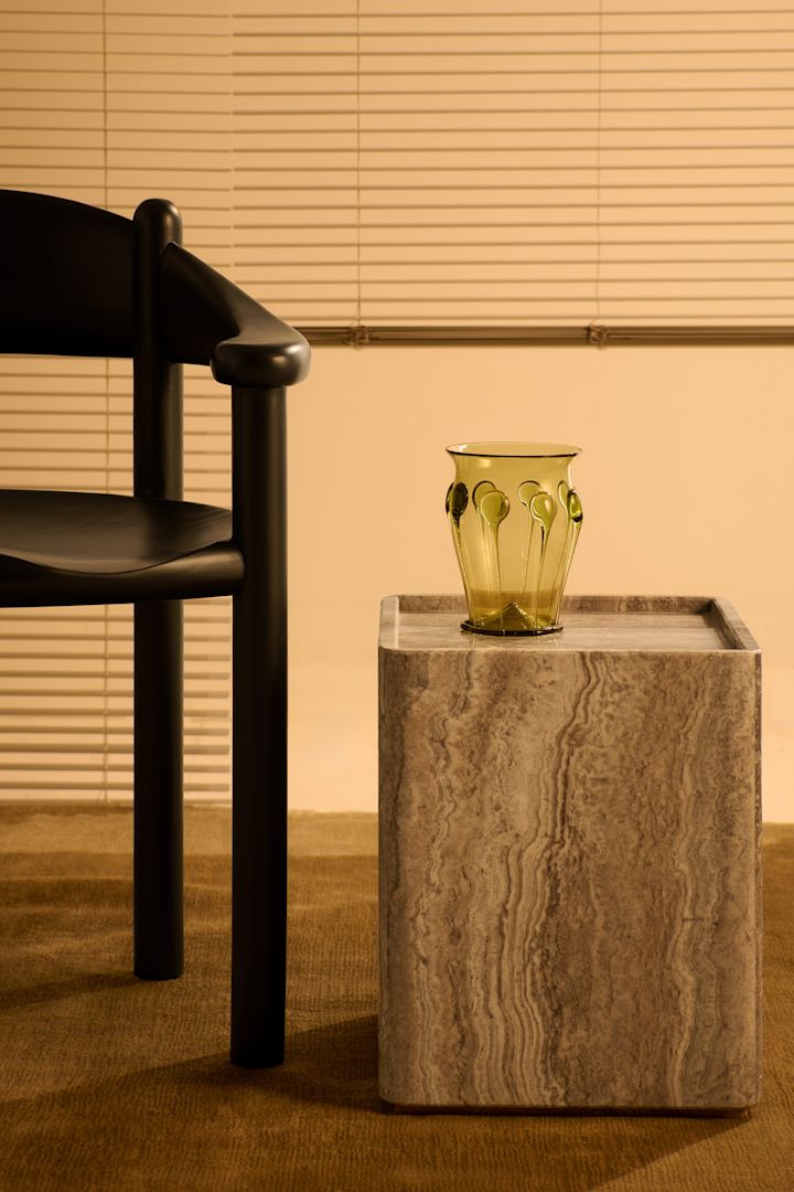 La pierre, l'une des tendances de la décoration intérieure de l'automne 2025, est ici présente sous la forme de la table d'appoint Peitra de Gubi, à côté d'une chaise surmontée d'un vase.