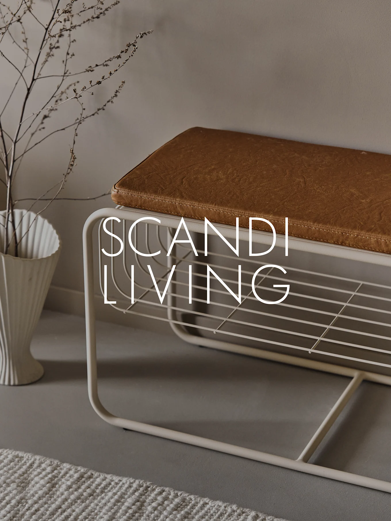 Banc d'entrée avec coussin marron, étagère à chaussures, vase blanc cannelé avec branches et texte 'SCANDI LIVING'.