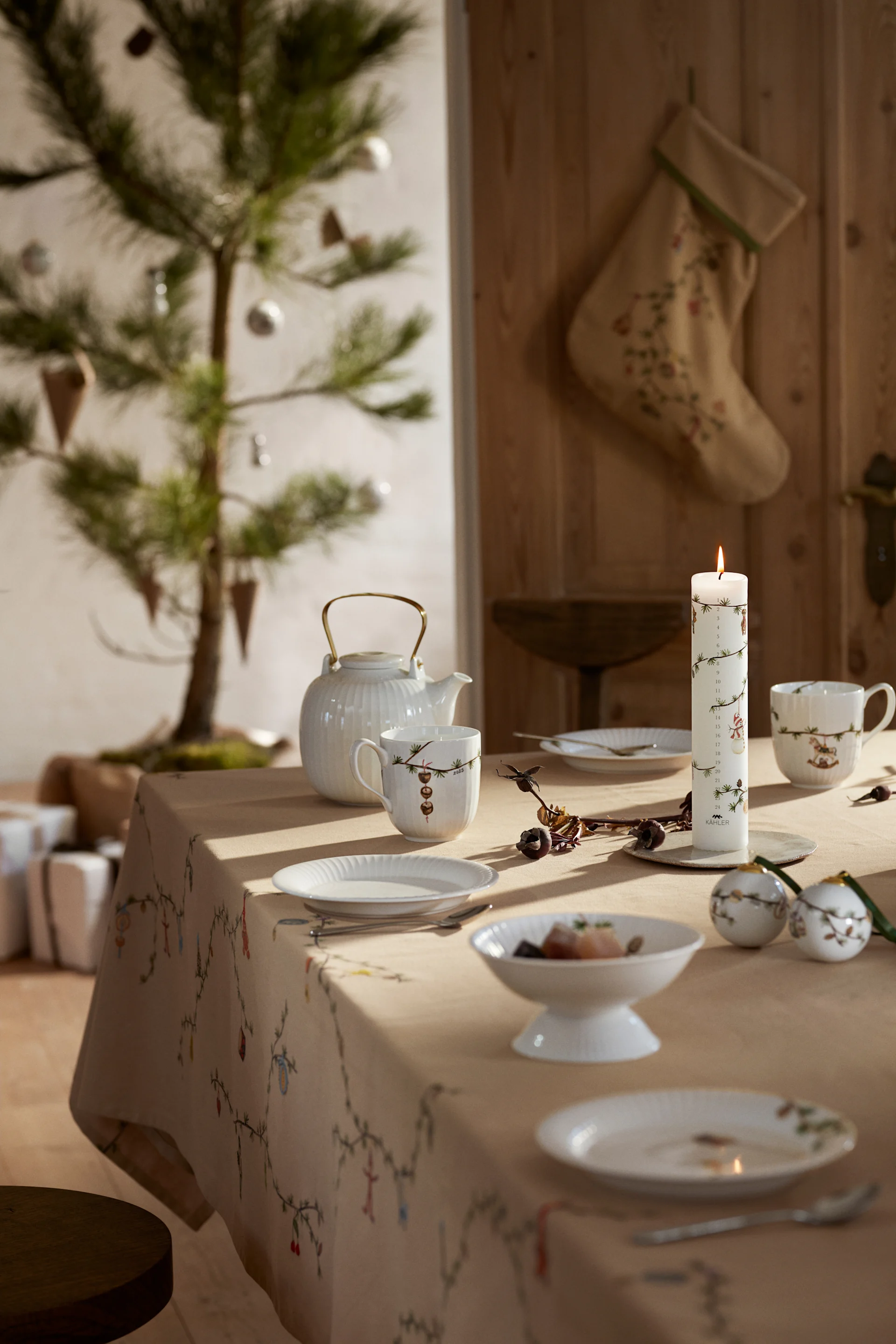 Une table de Noël dressée en Scandinavie avec une nappe et de la vaisselle de Noël de la collection Hammershøi de Kähler.