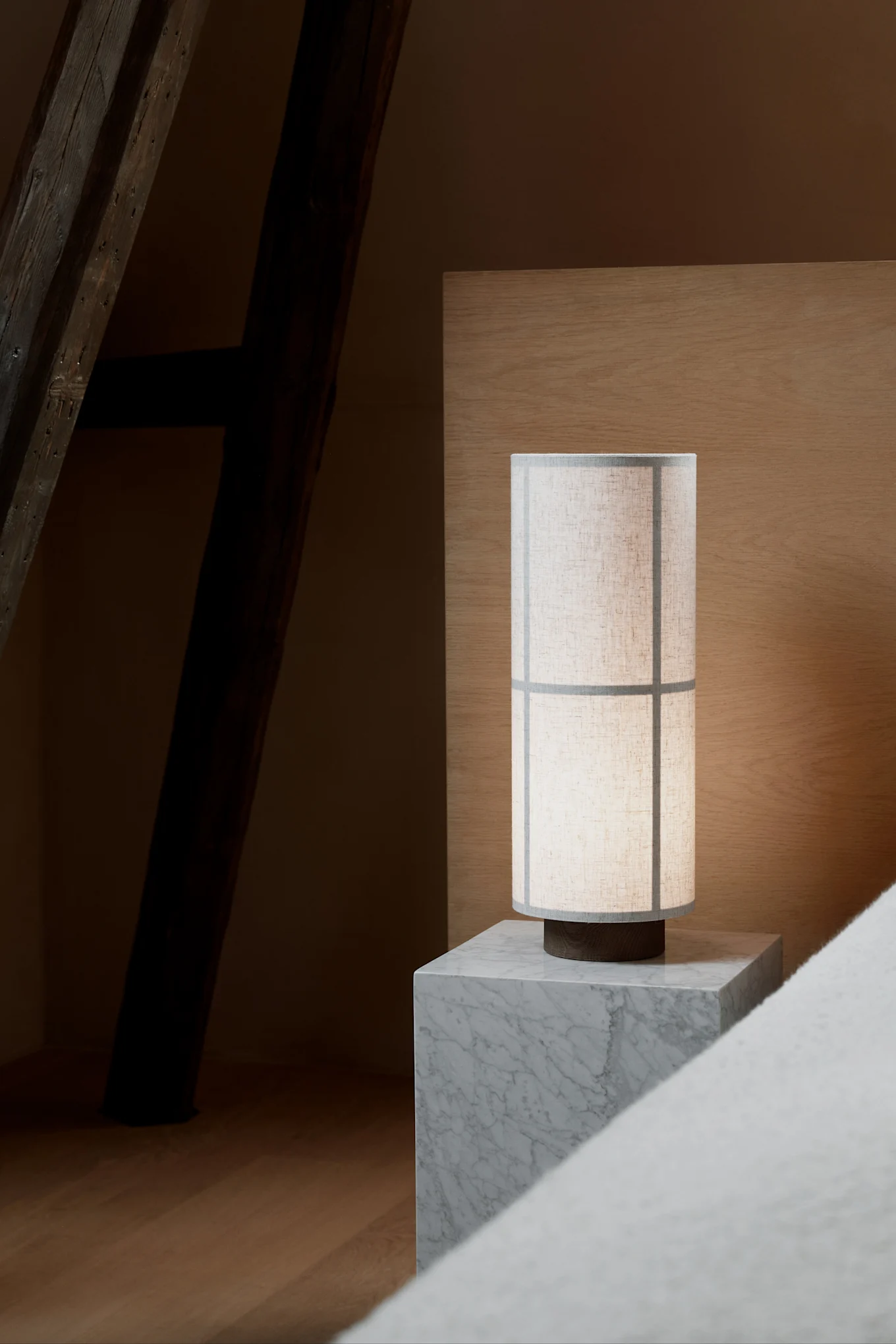 La lampe de table Hashira de style Japandi, signée Audo Copenhagen, trône sur une table de chevet en marbre gris.