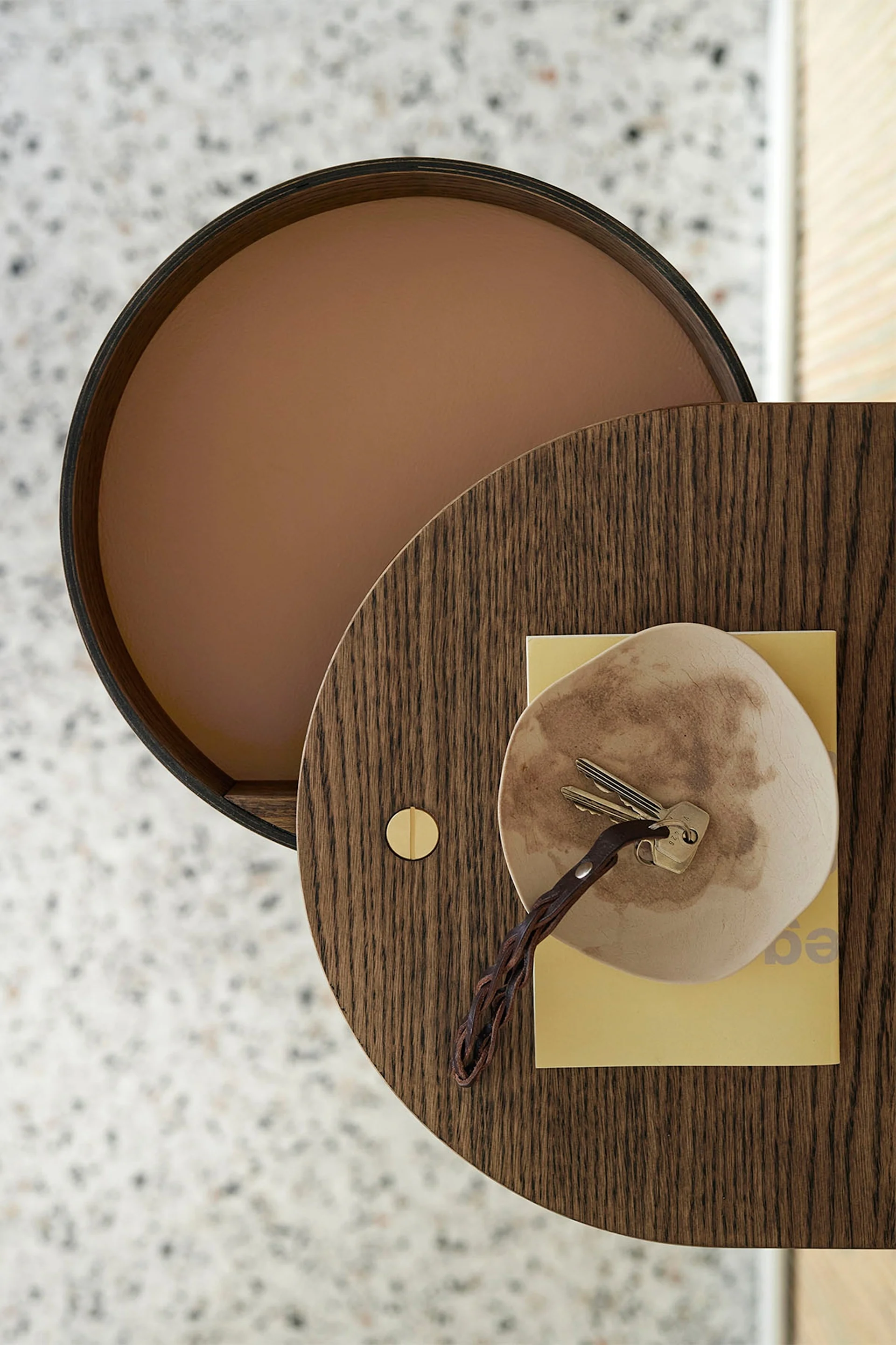 Vue de dessus d'une table en bois circulaire avec des clés sur un plat et un livre jaune.