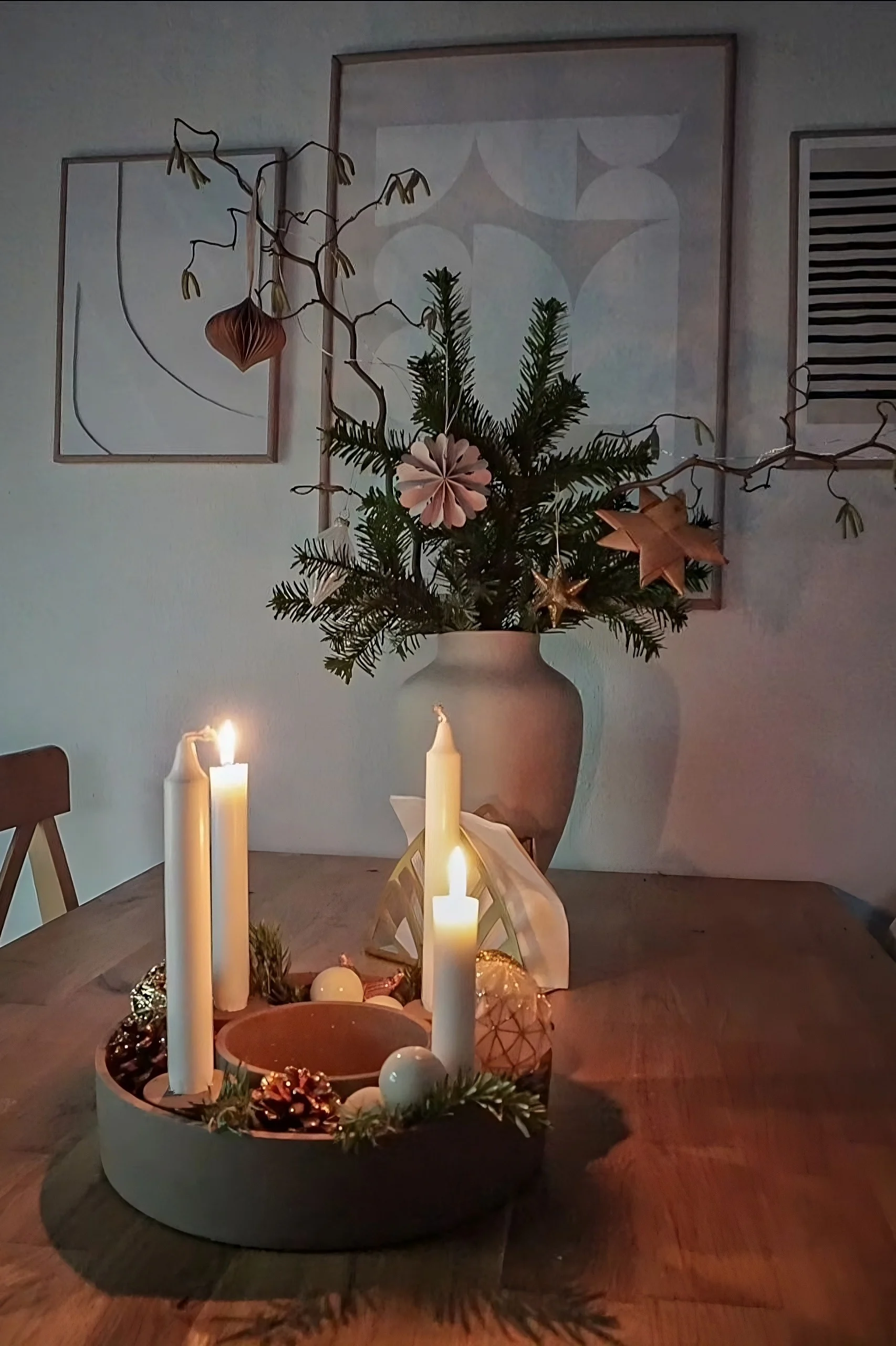 Le bougeoir The Ring de House Doctor, décoré de pommes de pin et de branches de sapin, est posé sur une table en bois.