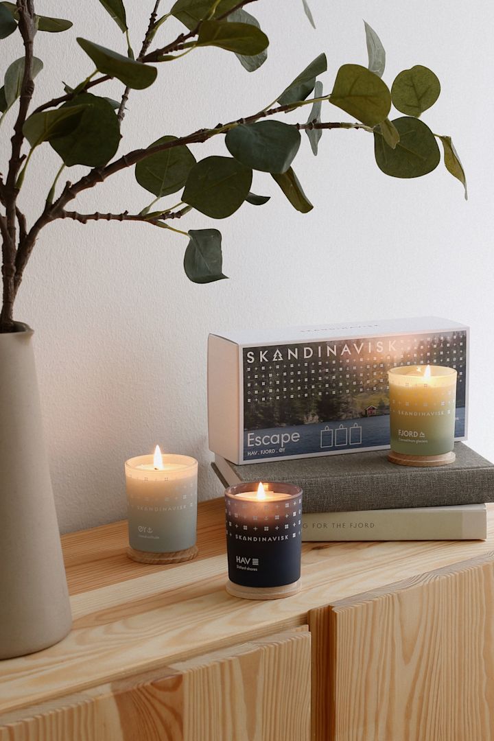 Cadeaux pour la fête des mères : Le coffret Escape trois pièces de Skandinavisk est ici présenté de manière décorative sur une commode en bois.
