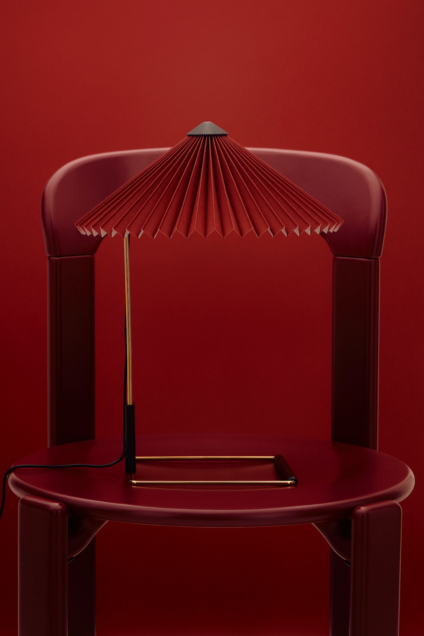 Le rouge cerise est l'une des tendances de 2025 en matière de couleurs d'intérieur. Ici, la lampe Matin est posée sur une chaise rouge sur un fond dans le même ton. 