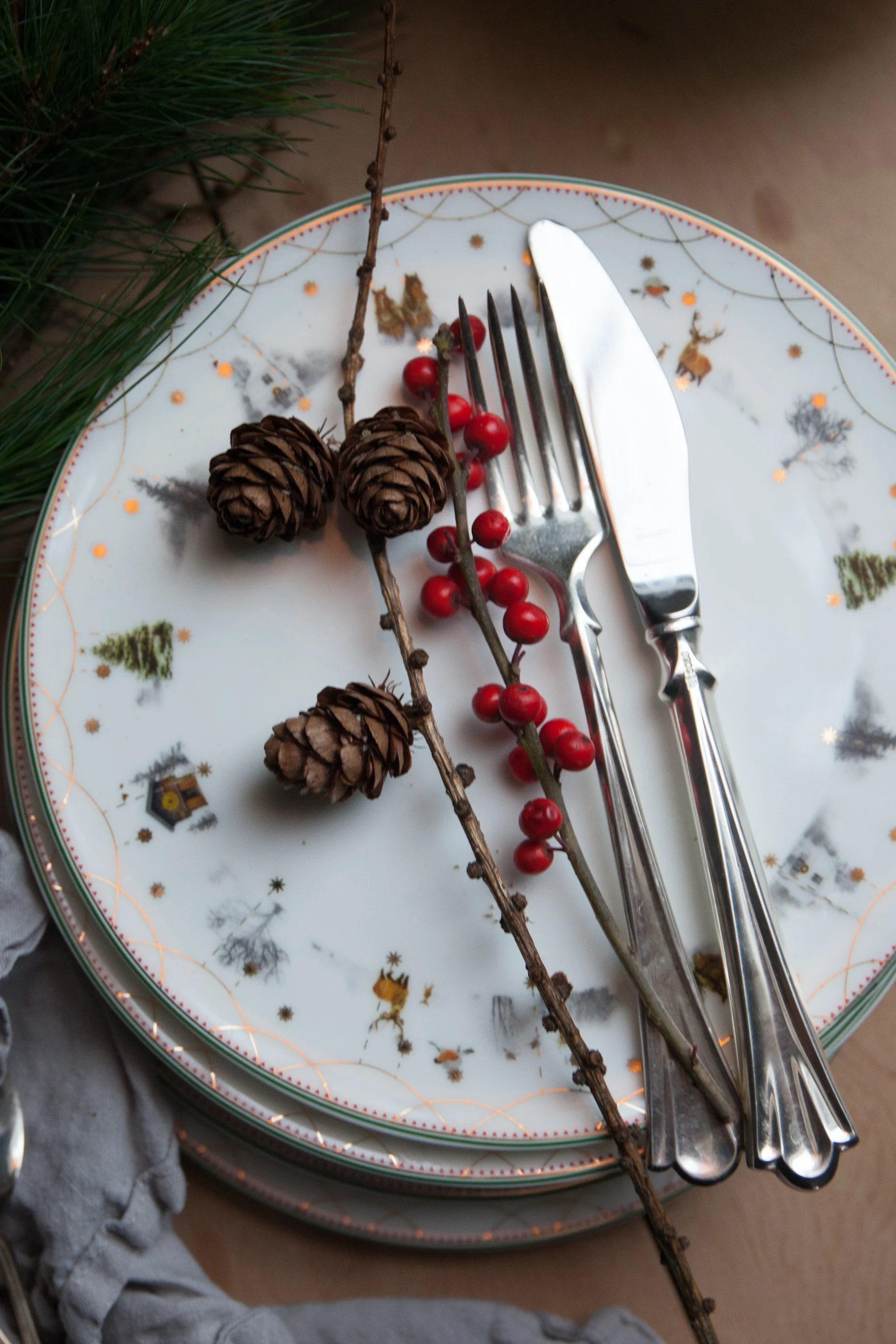 La vaisselle de Noël fait également partie de la décoration de Noël scandinave. Ici, une pile d’assiettes de la collection Julemorgen de Wik & Walsøe est posée sur une table, avec des couverts dessus.