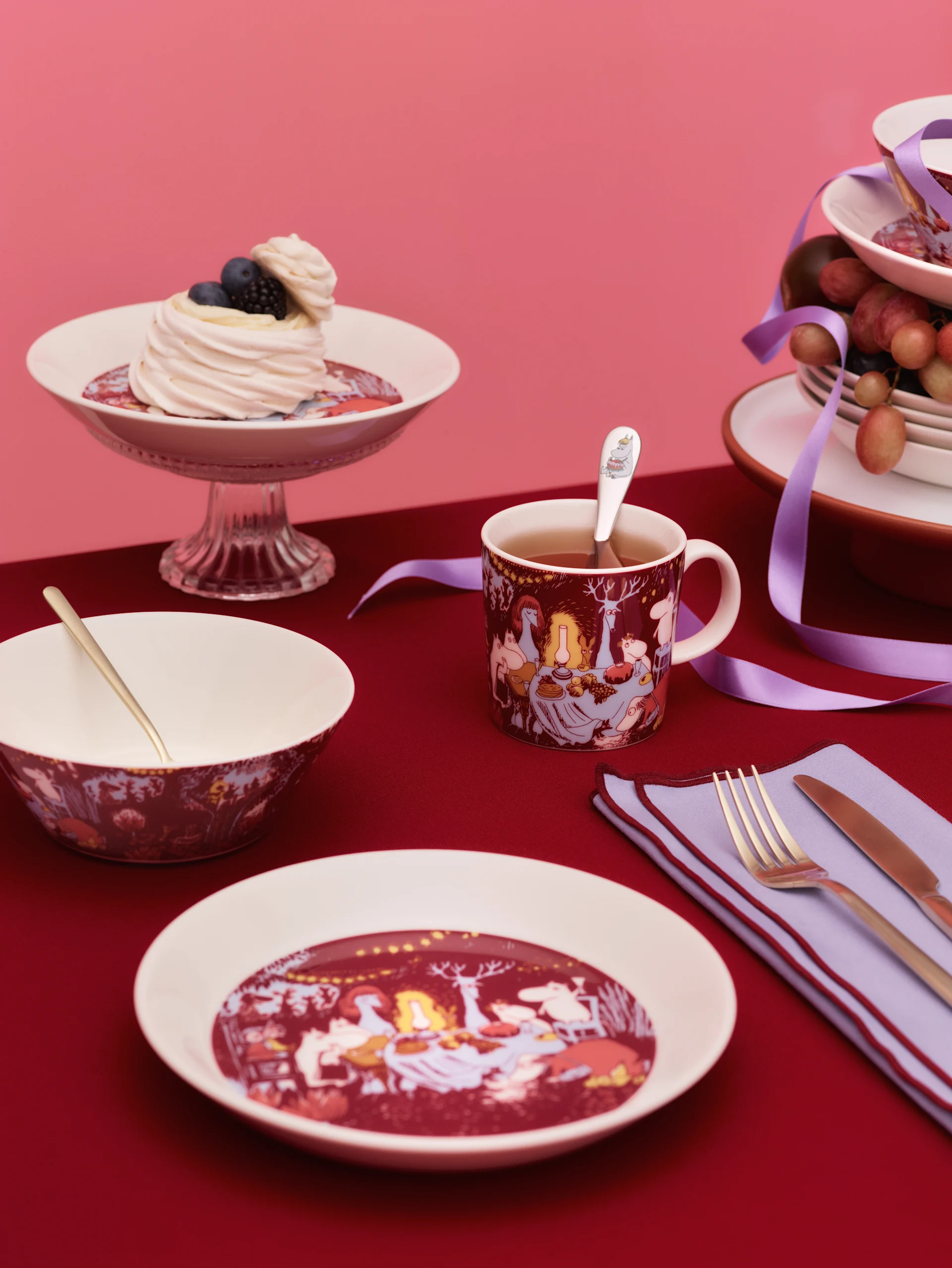 Sur une table dressée en rouge sont disposés différents produits de la collection Festive Moments de Moomin Arabia.