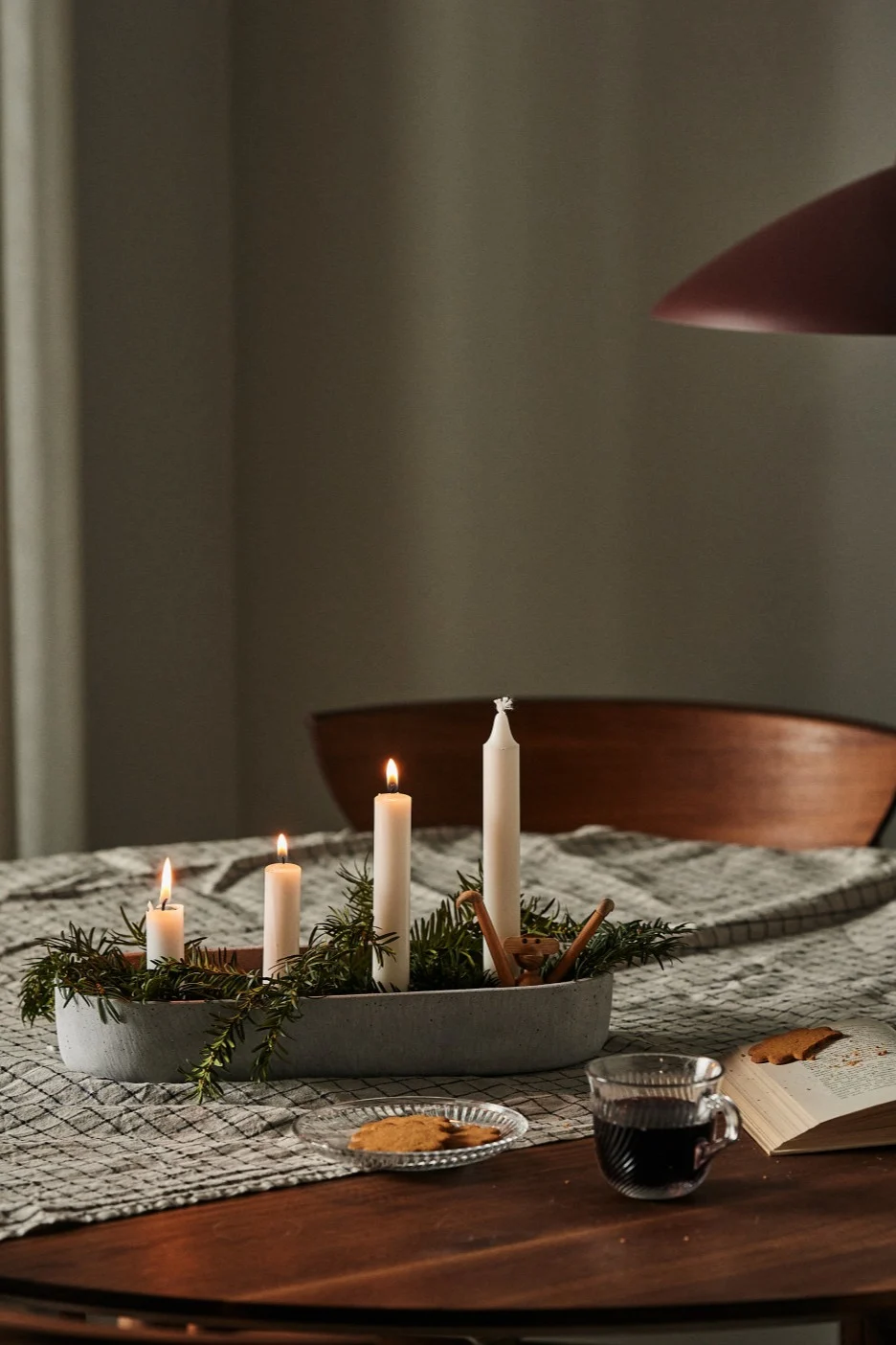 Un chandelier de l'Avent avec de vraies bougies est posé sur une table à manger et diffuse une ambiance de Noël. 