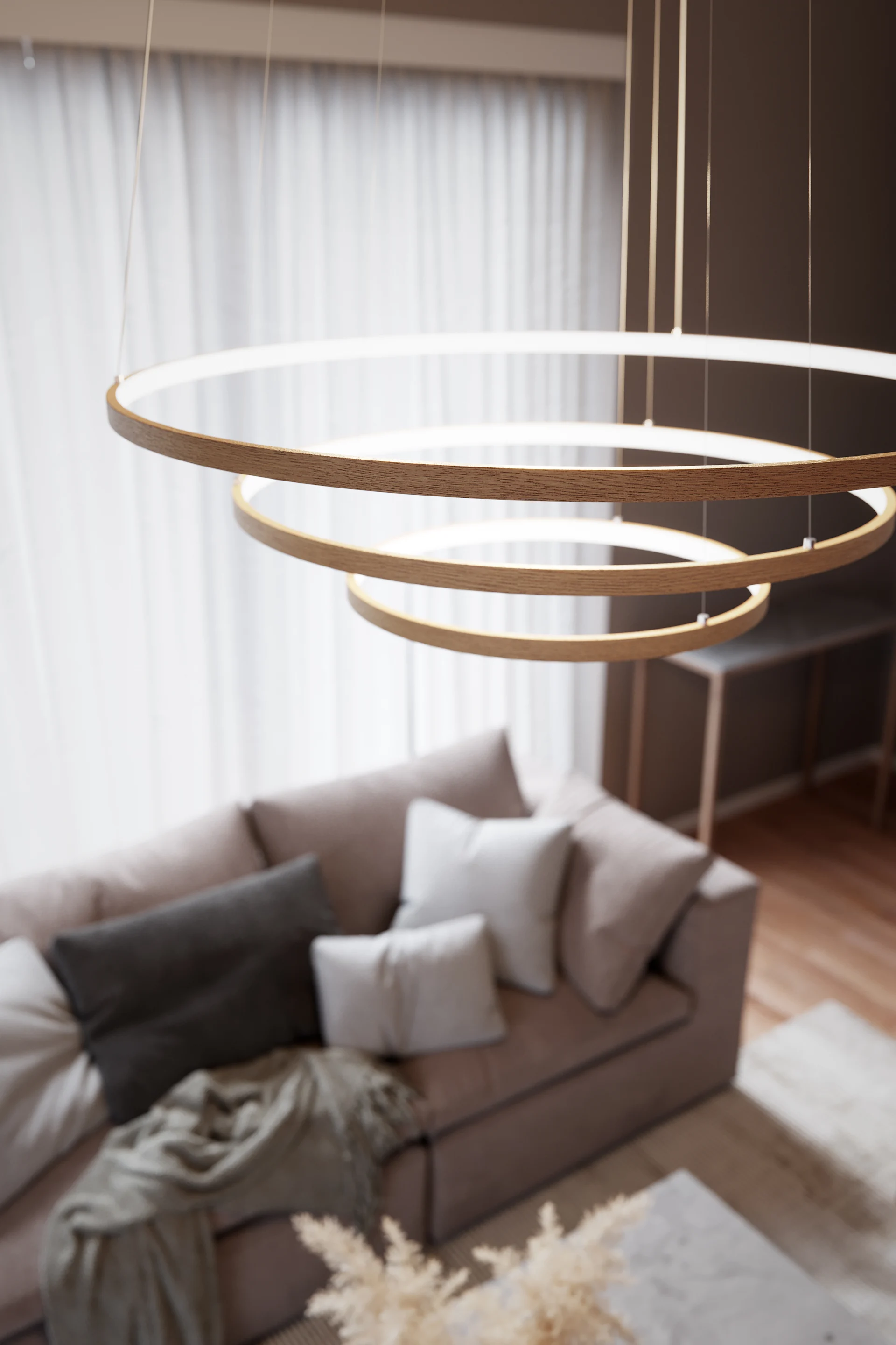 Au-dessus d'un canapé beige est suspendu le luminaire scandinave Trione de By Rydens.