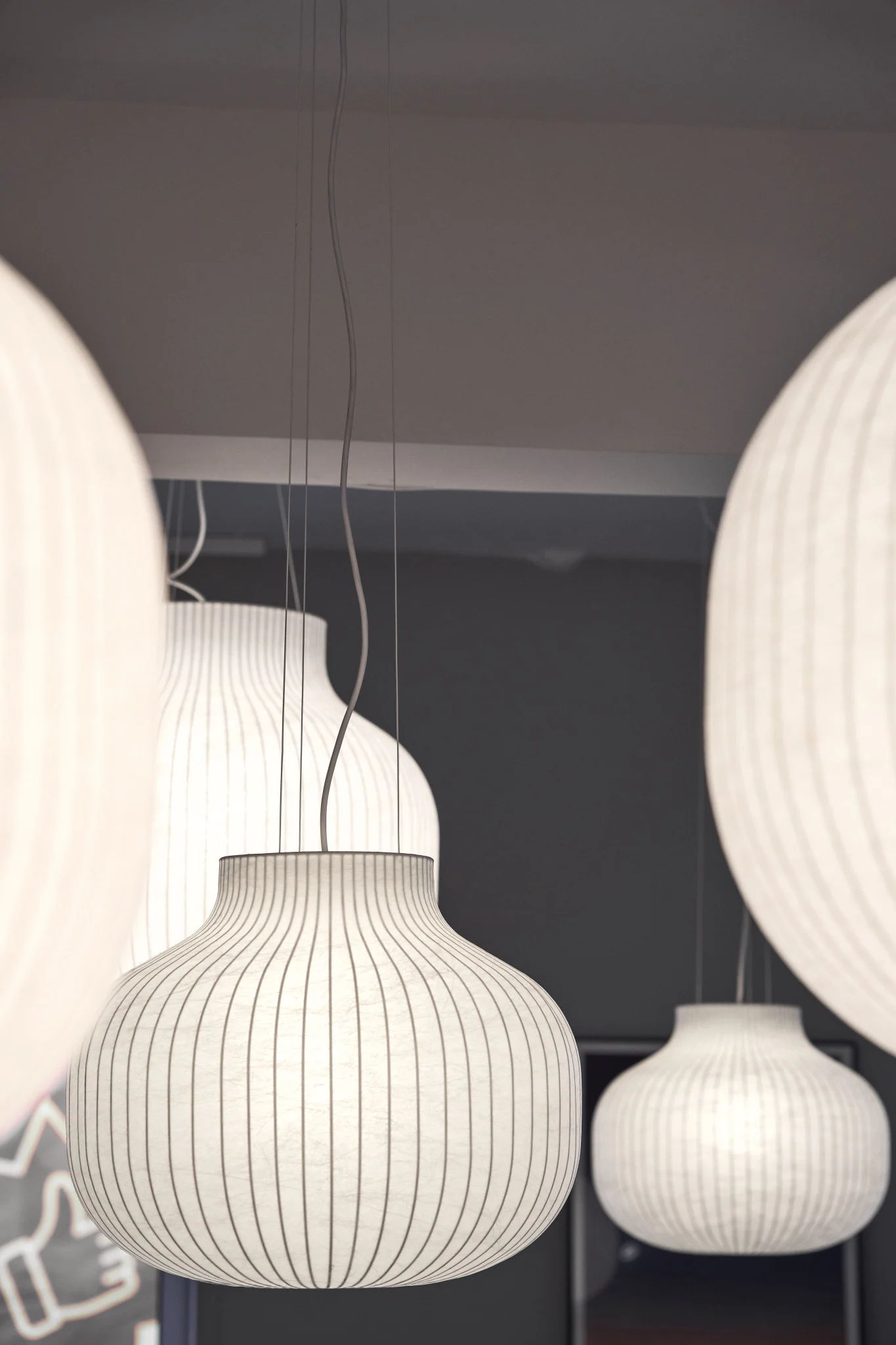 Les lampes avec abat-jour en papier sont l'une des tendances intérieures de l'automne 2025. Ici, plusieurs lampes suspendues Strand de Muuto sont accrochées au plafond.