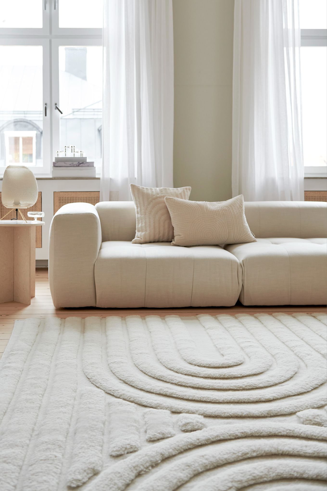 Tapis pour le salon : Le tapis en laine clair Curve de Classic Collection est placé devant un canapé dans un salon clair et lumineux.