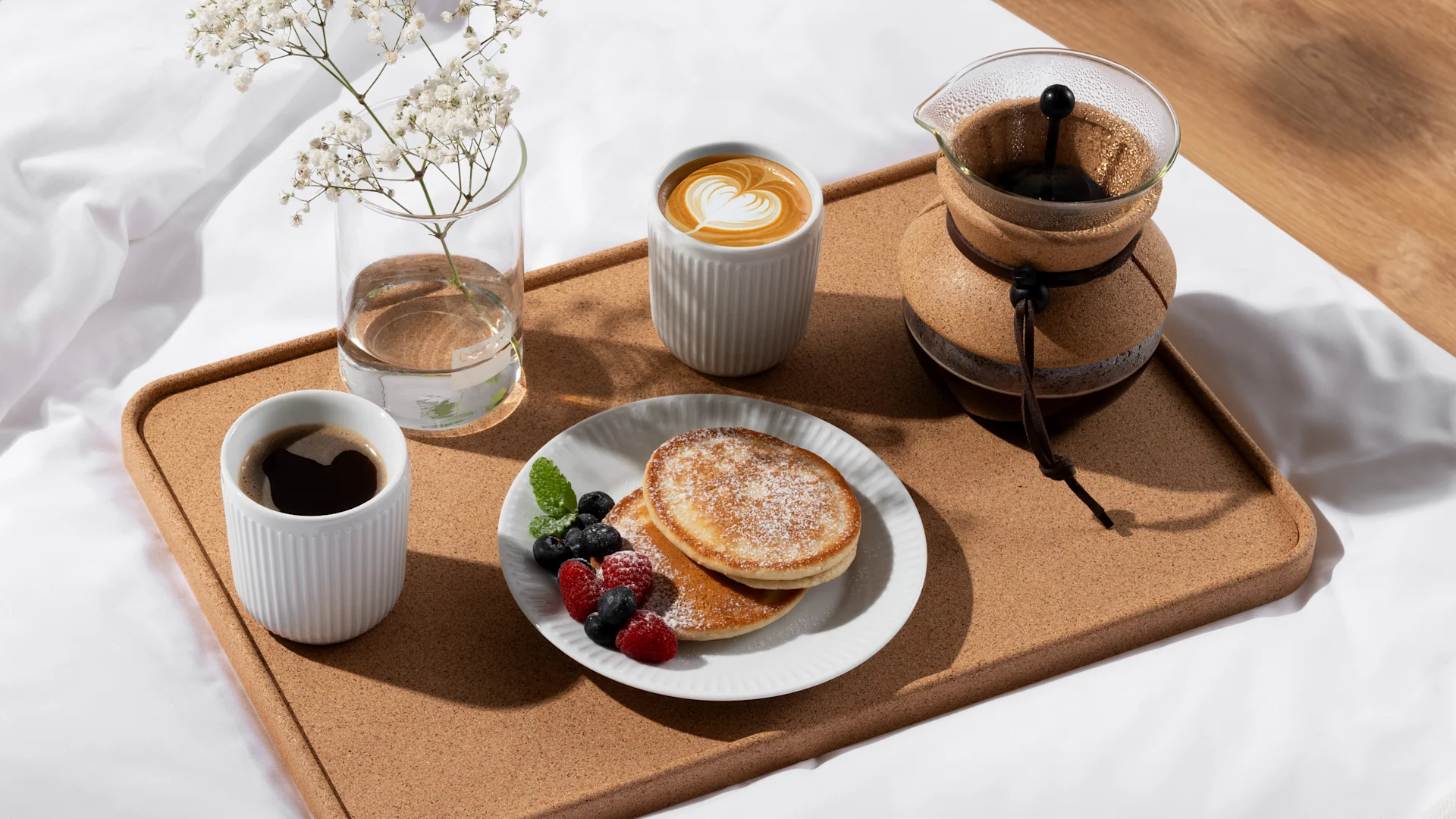 Surprenez votre moitié pour la Saint-Valentin en lui apportant le petit-déjeuner au lit. Ici, une tasse de café et une assiette, toutes deux de la marque Bodum, sont posées sur un plateau sur le lit.