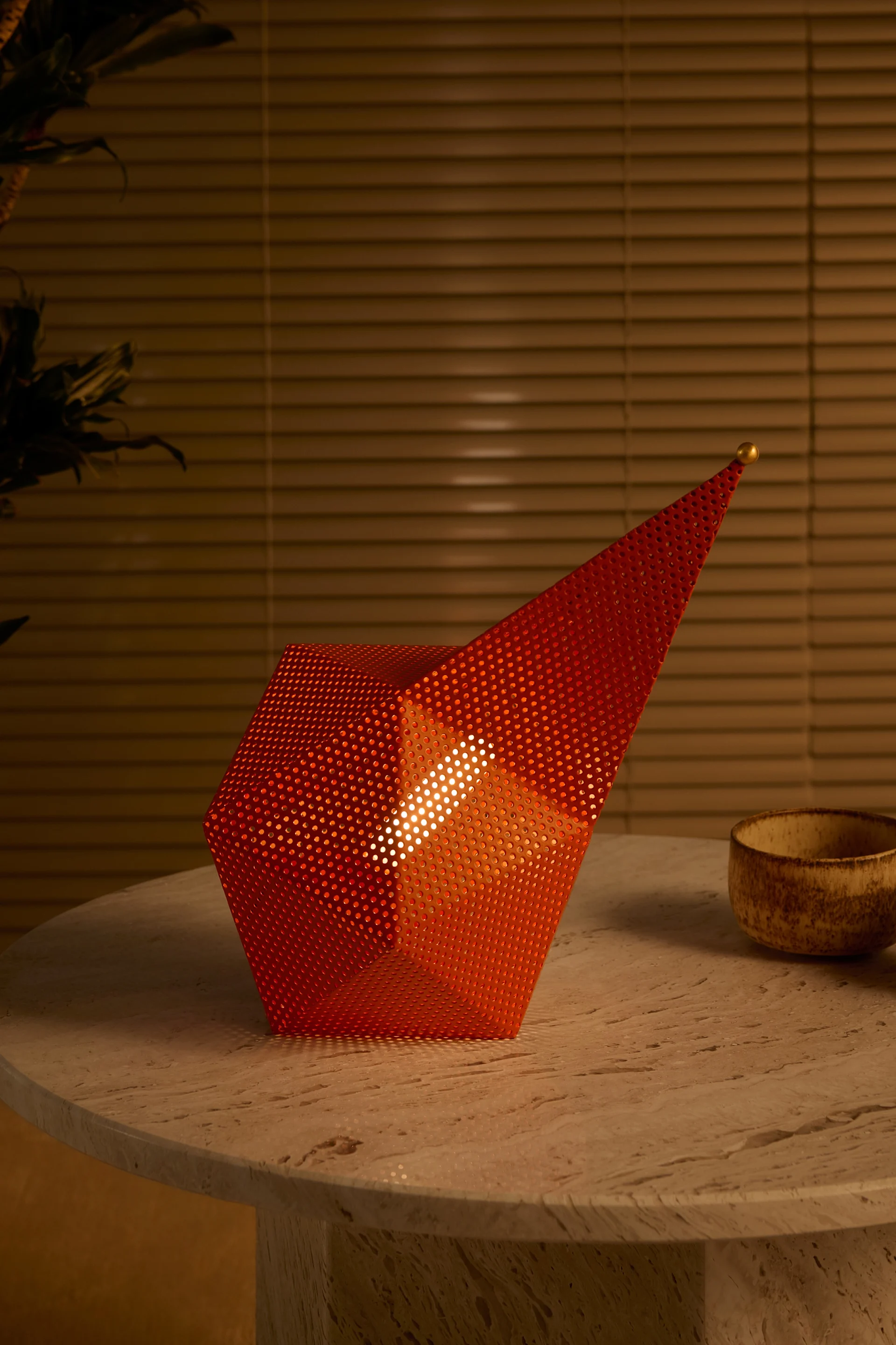Les années 60 et 70 sont remises au goût du jour avec les tendances de l'automne 2025 en matière de décoration d'intérieur : ici, la lampe de table portable orange de Gubi est posée sur une table en bois.