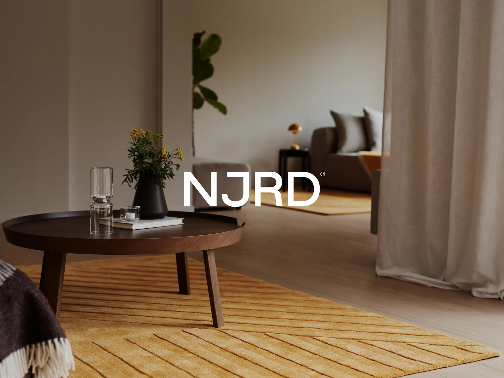 Un salon chaleureux avec une table basse ronde en bois avec des fleurs et un verre, et un tapis jaune texturé.