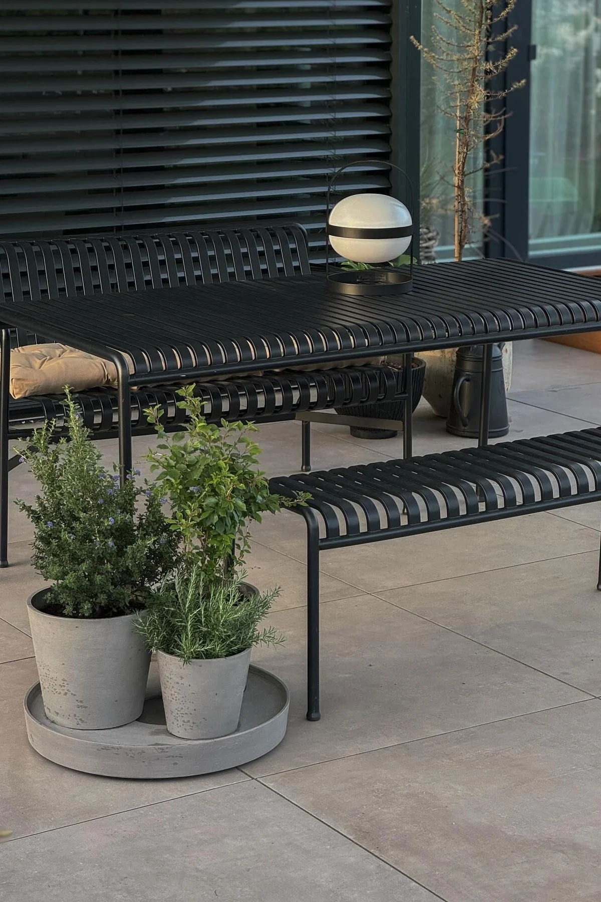 Des meubles de jardin de la collection Palissade sont installés sur la terrasse de @grauschwarzliebe, devant des pots de fleurs avec des herbes aromatiques à l'intérieur et sur la table se trouve une lampe solaire Soft Spot de Rosendahl.