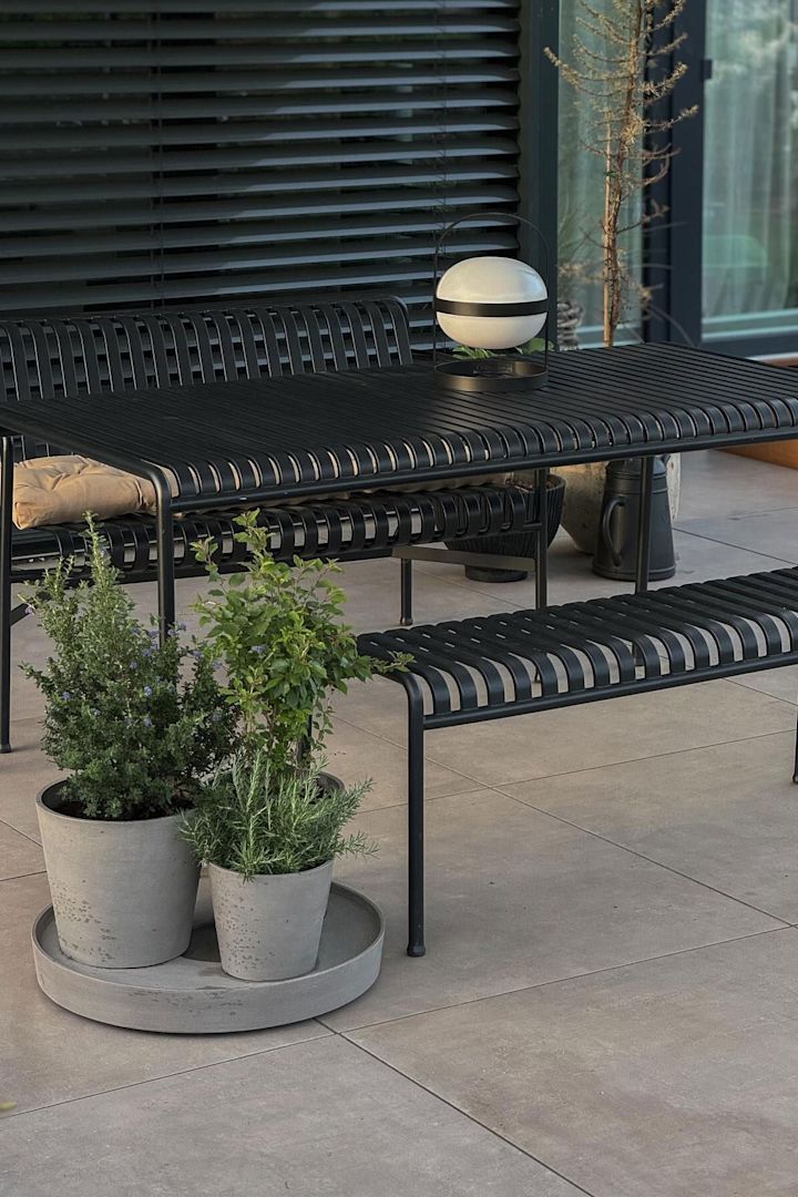 Des meubles de jardin de la collection Palissade sont installés sur la terrasse de @grauschwarzliebe, devant des pots de fleurs avec des herbes aromatiques à l'intérieur et sur la table se trouve une lampe solaire Soft Spot de Rosendahl.