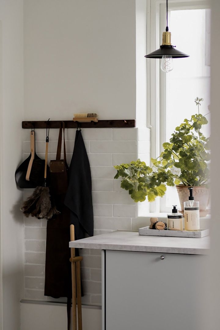Les petites lampes suspendues offrent un éclairage ponctuel dans la cuisine. Ici, la mini-lampe suspendue Disc en noir de Globen Lighting est suspendue dans une cuisine devant une fenêtre.