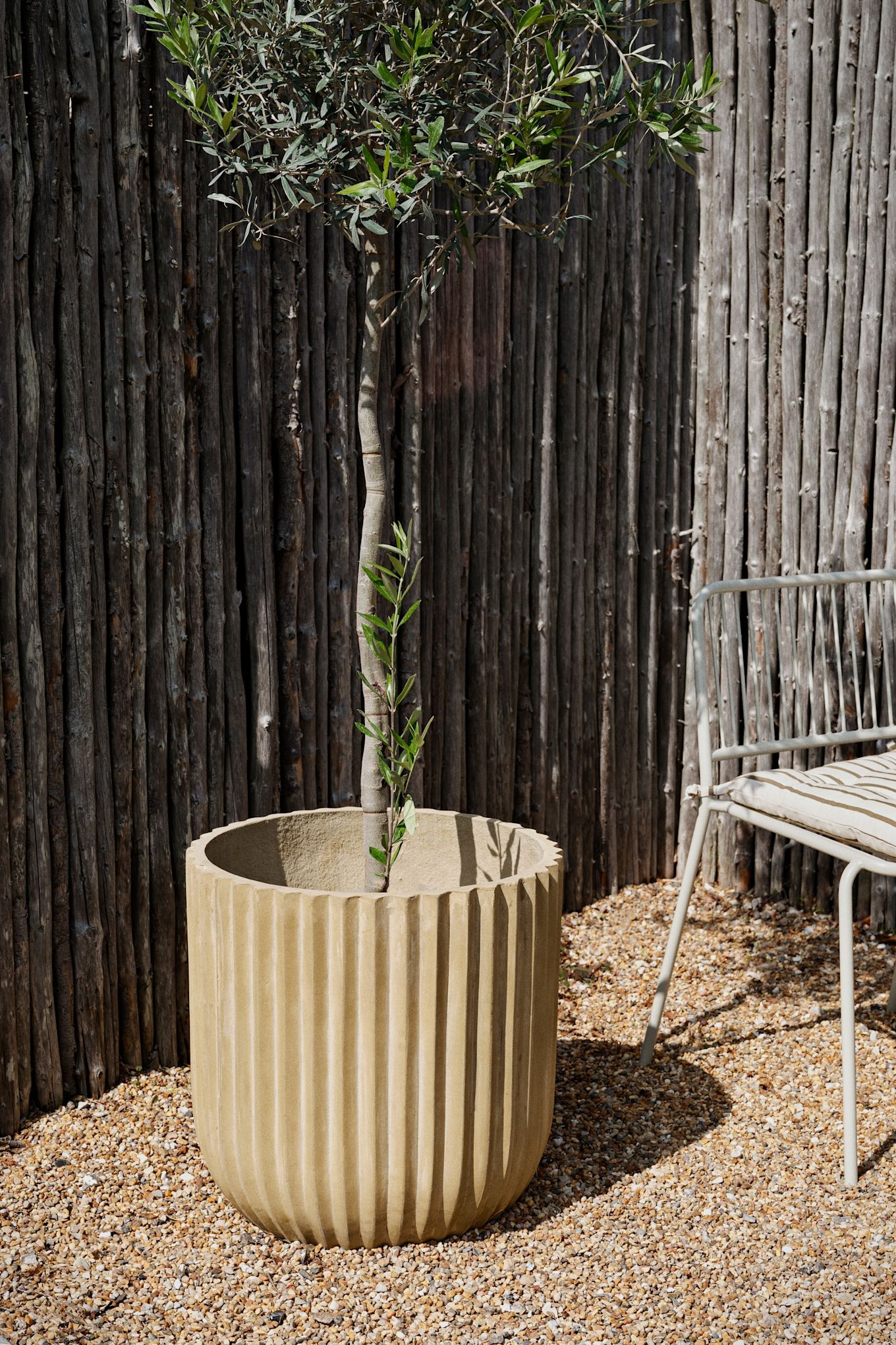 La jardinière d'extérieur en fibre rustique de Broste Copenhagen se trouve dans un jardin.