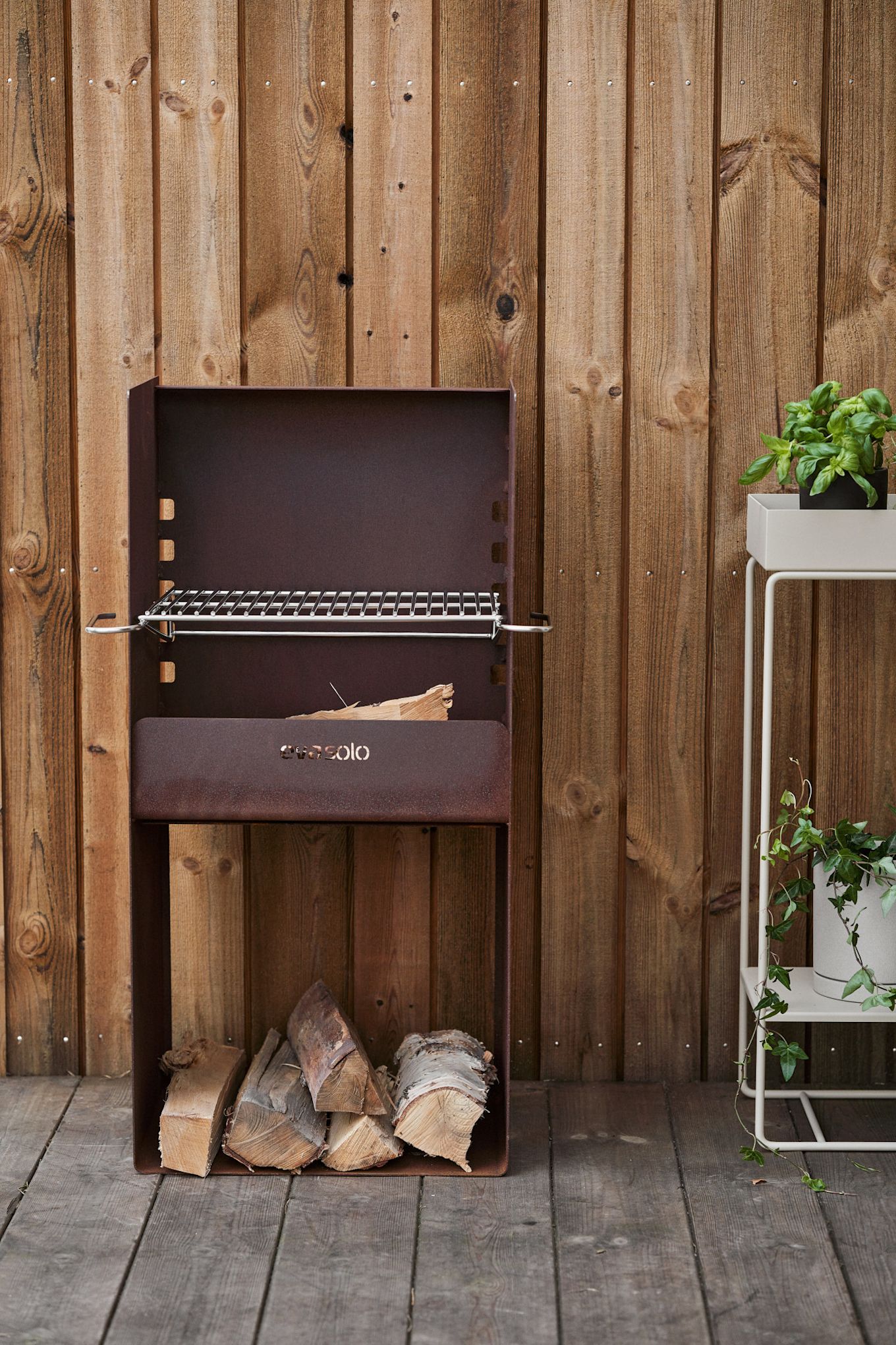 Le barbecue rustique FireSpot d'Eva Solo se trouve sur une terrasse en bois.