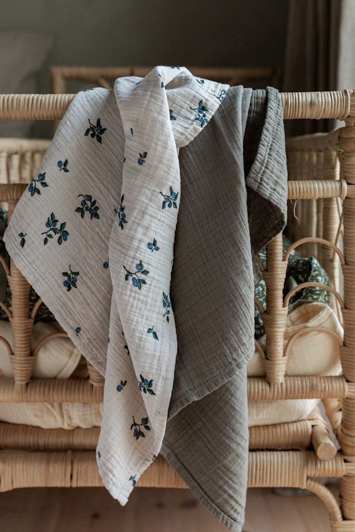Les couvertures Blueberry Muslin de Garbo&Friends, qui sont ici suspendues au-dessus d'une balustrade de lit, ne servent pas seulement de doudou mais aussi de bavoir, ce qui en fait un cadeau très pratique pour une baby shower.