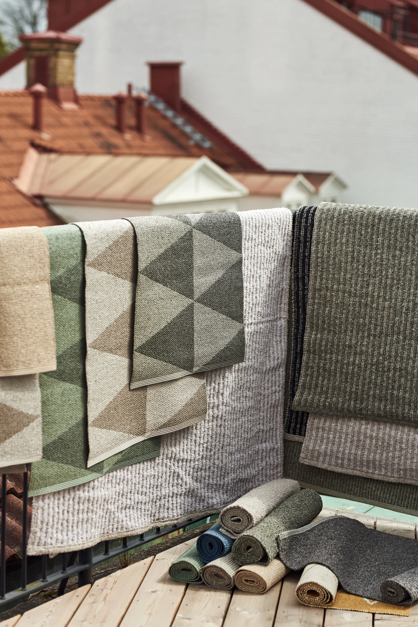 Tapis d'extérieur : vous voyez ici les nombreux tapis d'extérieur de Scandi Living de différentes tailles, matériaux et couleurs suspendus au-dessus d'une balustrade de balcon.