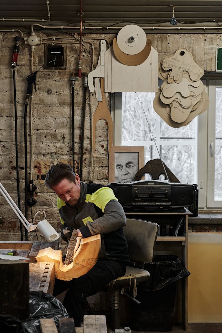 Un homme sculpte un moule en bois destiné à la création du vase Alvar Aalto.