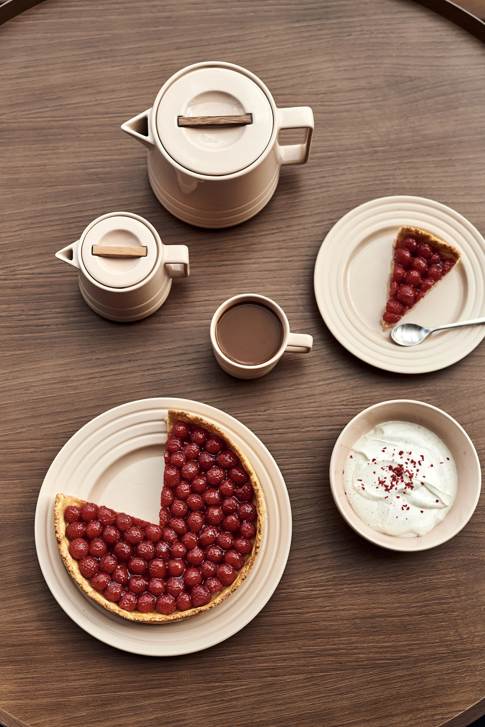 Que diriez-vous d'un nouveau service de vaisselle à offrir pour la fête des mères ? Vous voyez ici des assiettes beiges de différentes tailles avec des gâteaux, une tasse, une théière, un bol et un pot à lait de la collection Lines de NJRD.